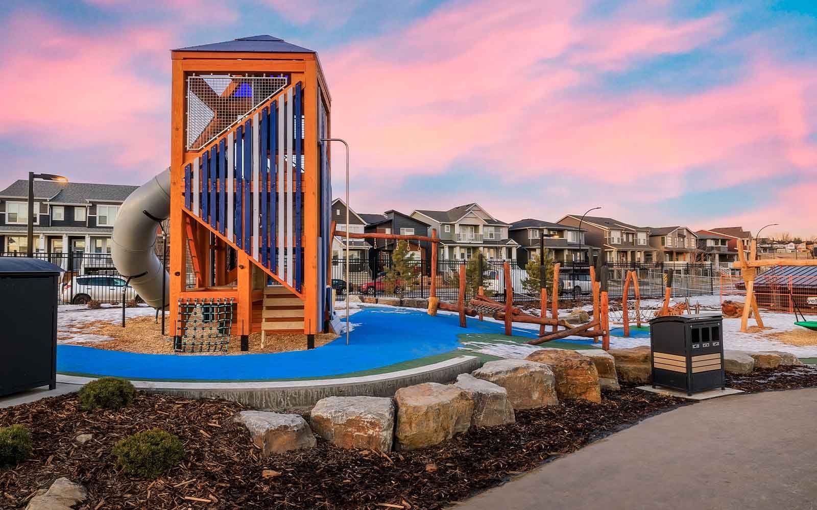 Rockland Park NW Calgary modern orange and blue climbing tower structure at the community playground during dusk.