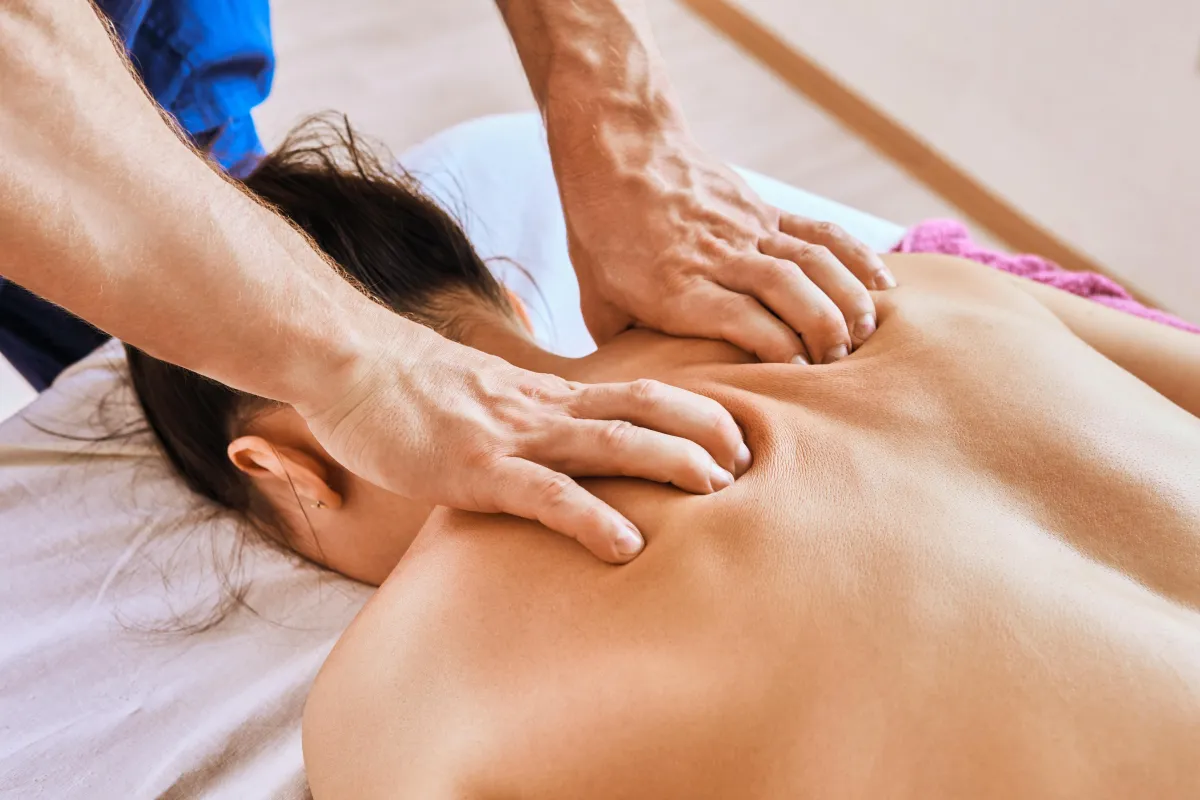 Licensed massage therapist performing deep tissue back massage in Regina clinic.