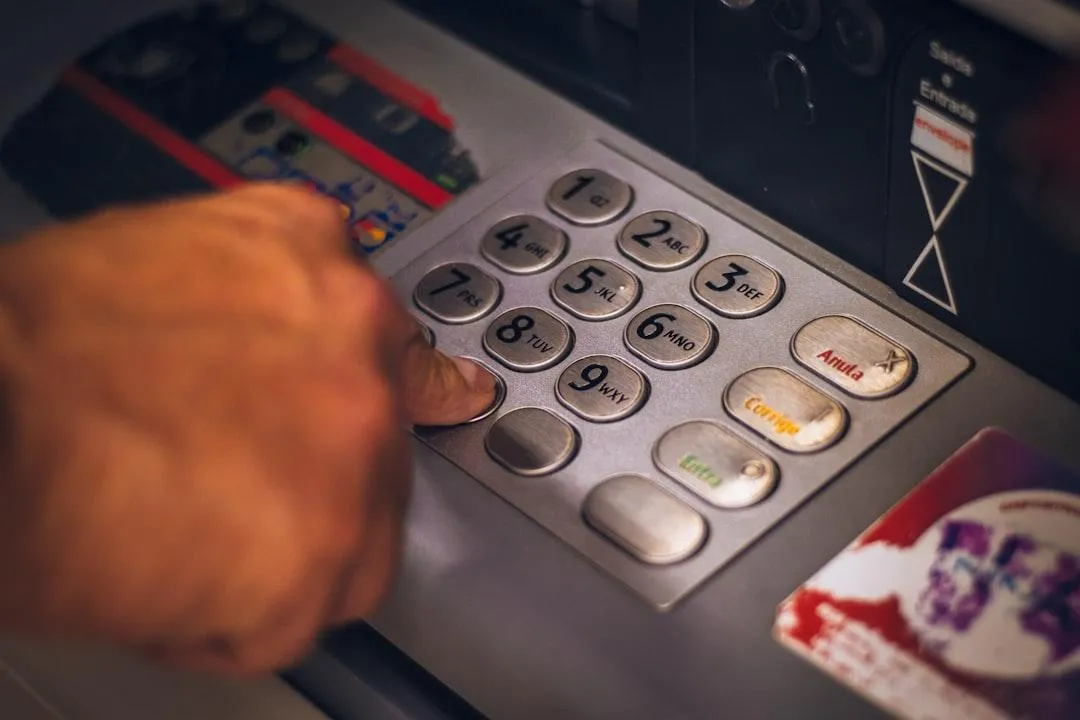 Finger pressing keypad at a bank ATM, symbolizing personal banking strategies, financial control, and leveraging money like a bank