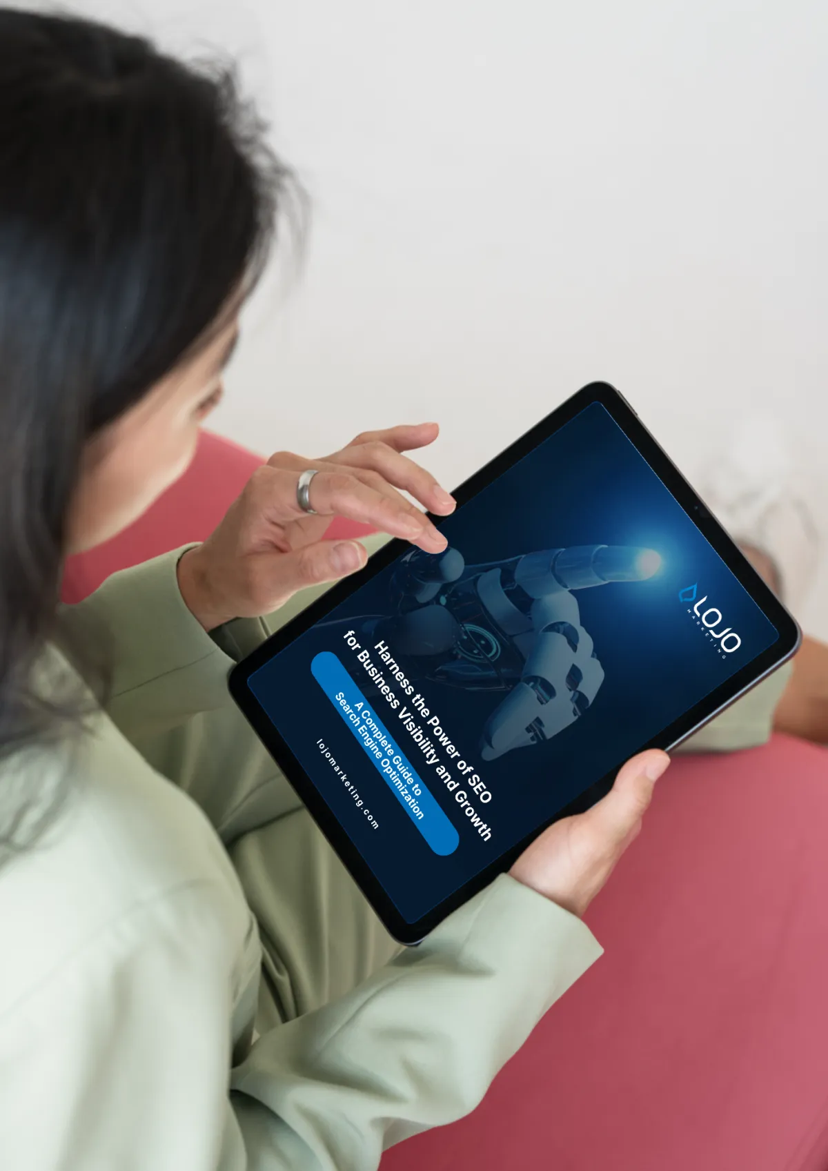 Woman using a tablet displaying "Harness the Power of SEO for Business Visibility and Growth" with LOJO Marketing branding, emphasizing search engine optimization strategies.