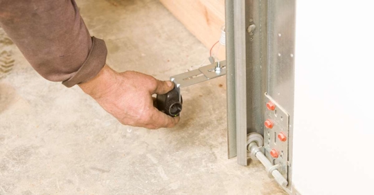 Man adjusting garage door opener safety reverse sensor