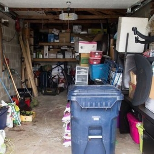 A cluttered garage is filled with boxes, tools, and storage containers.