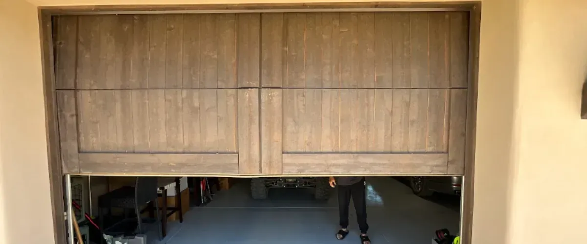Modern wood garage door partially open inside a residential garage.