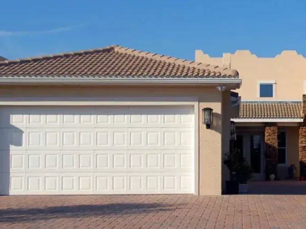 White garage door installed on a stucco home with a tile roof and paver driveway