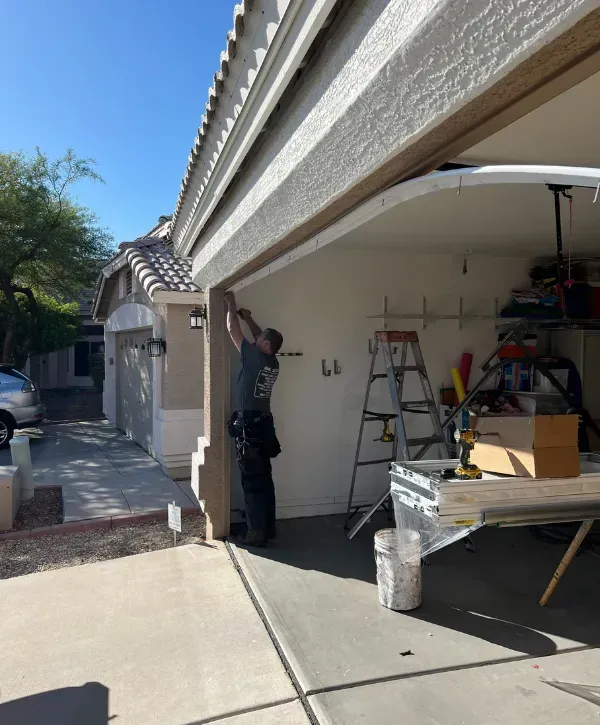 Technician adjusting the garage door frame from outside the house