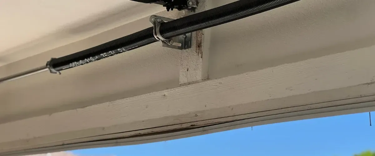 Close-up view of a garage door torsion spring mounted above the door frame.