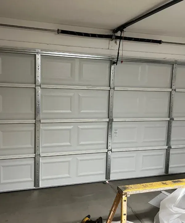A close-up view of the top part of a gray garage door with its internal spring mechanism visible.