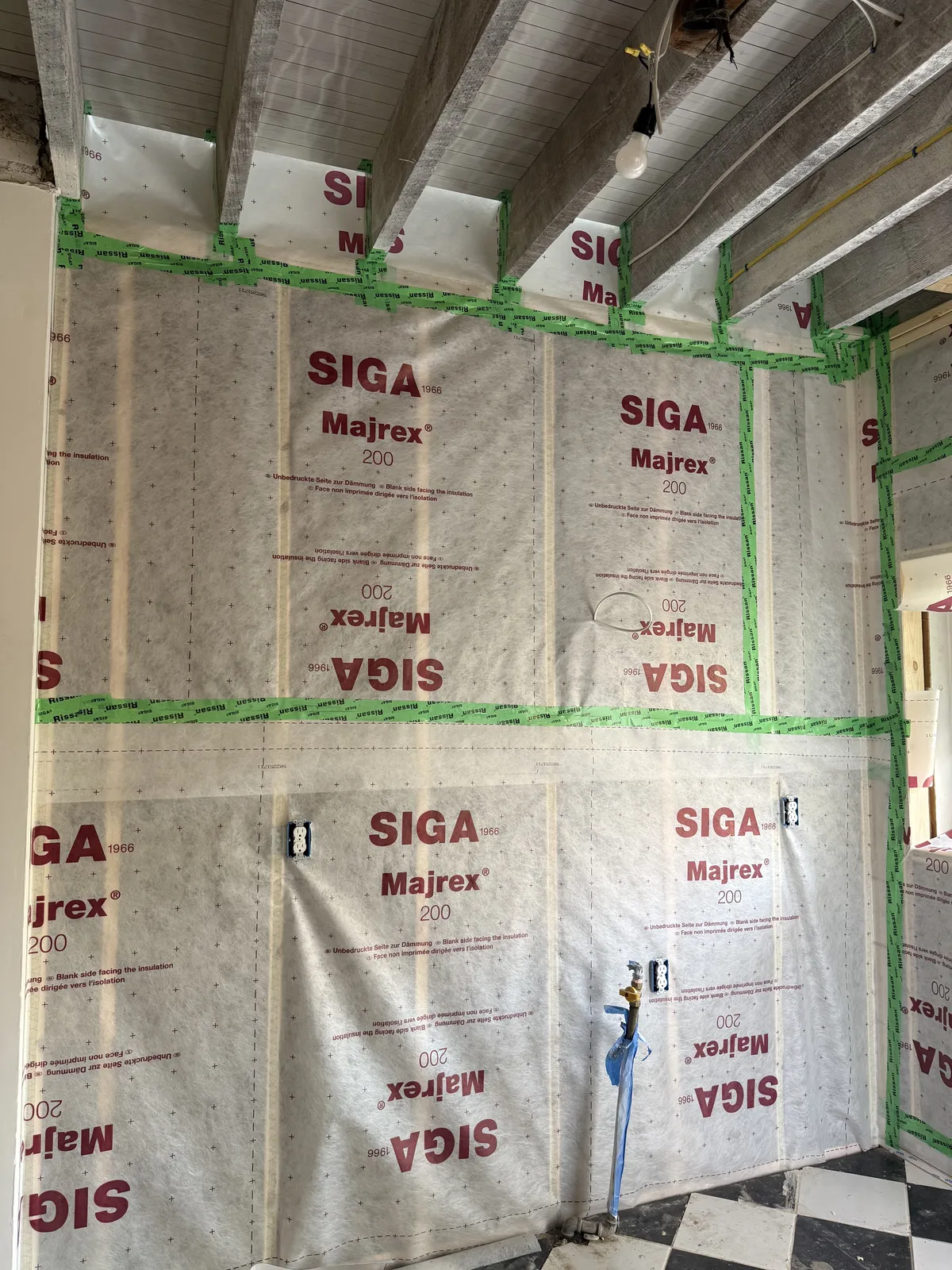 Architectural high-performance retrofit in progress showing precision air-barrier installation on historic Baltimore masonry rowhouse