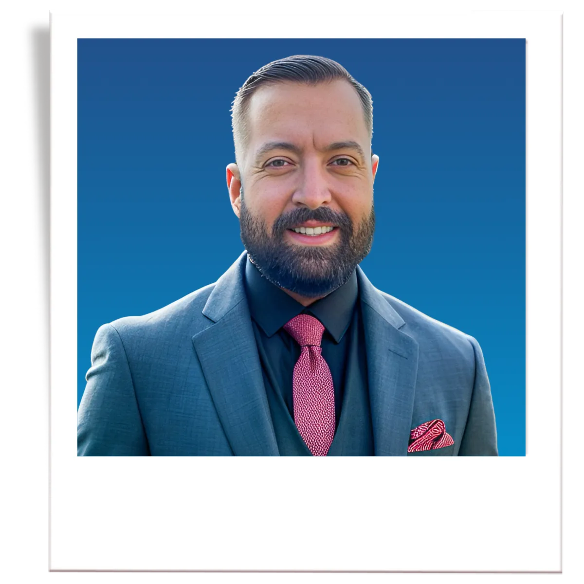A picture of professional insurance agent, Noe Recendez. The picture is in the style of a polaroid. The insurance agent is wearing a dark grey men's blazer, a blue button down shirt, and a black tie. The agent is in front of a blue gradient background. 