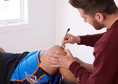 Massaging Left Knee — Wichita, KS — Advanced Chiropractic