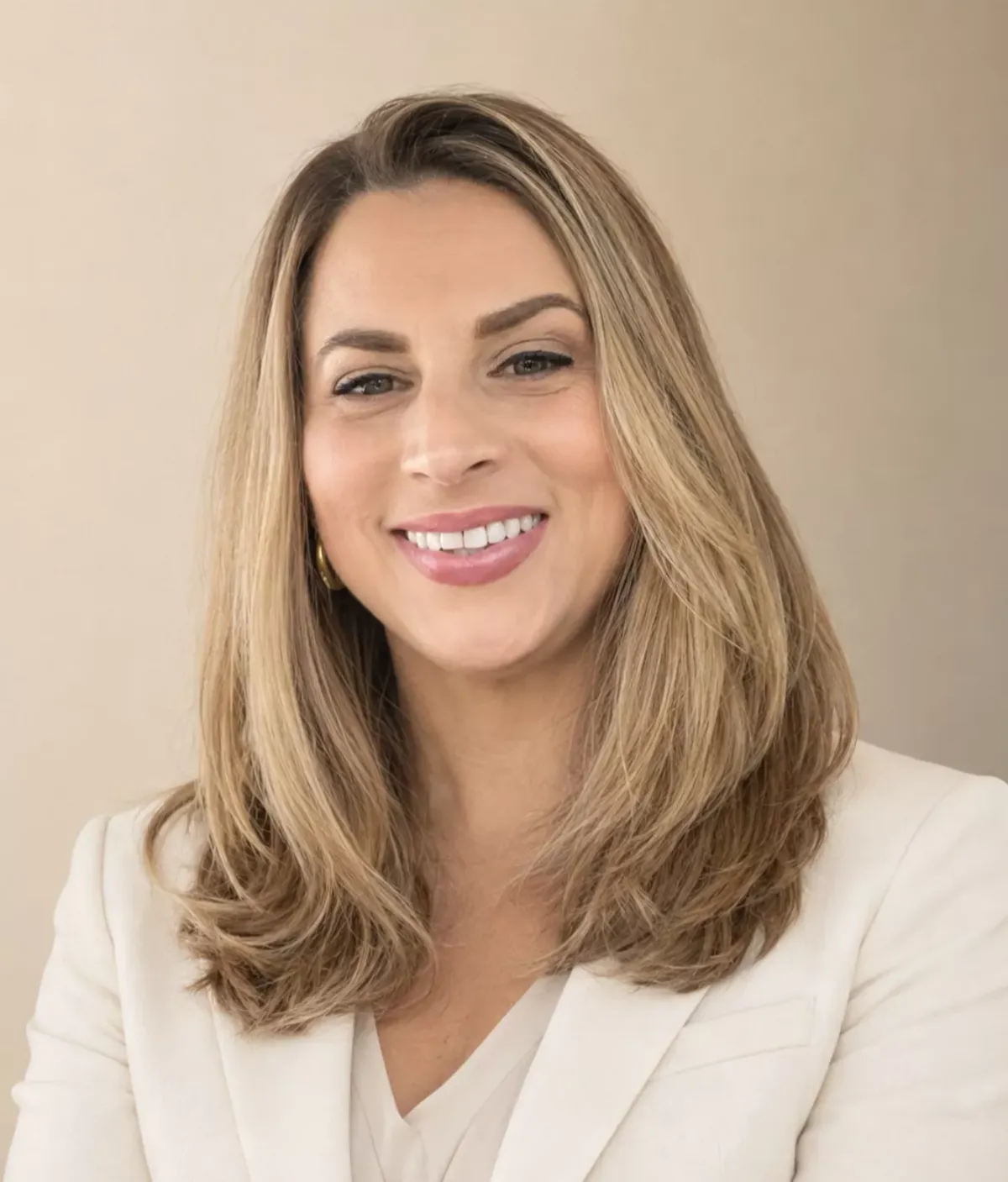 A smiling blonde woman in a white blazer, framed in an arch shape against a light background.