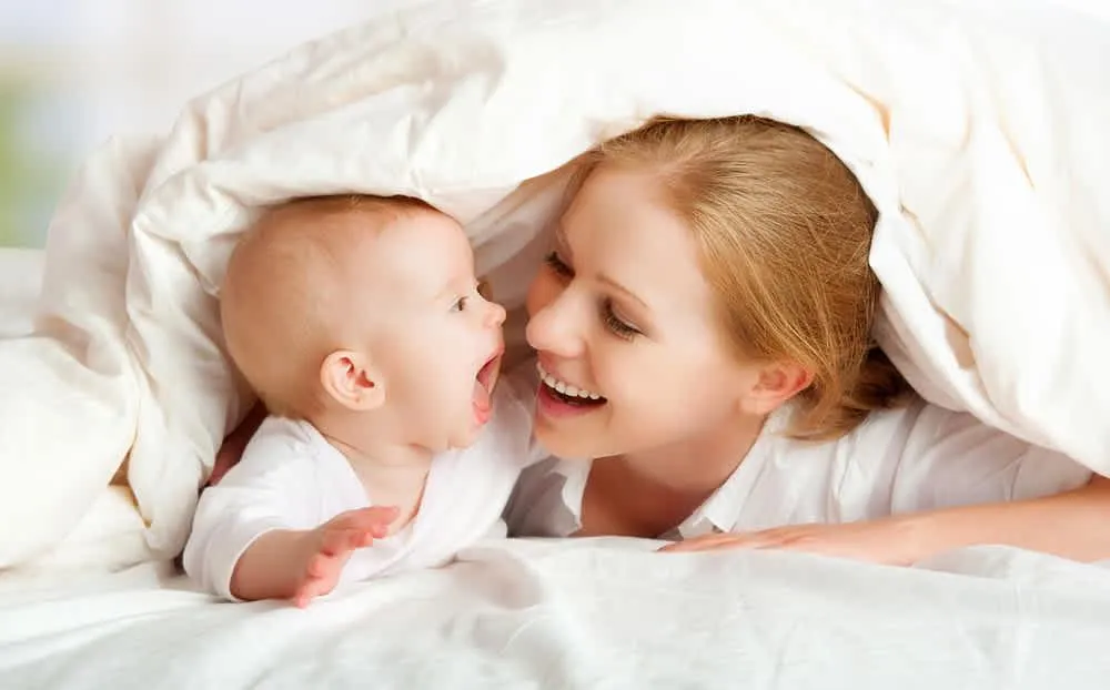 baby laying on bed while woman massaging his back