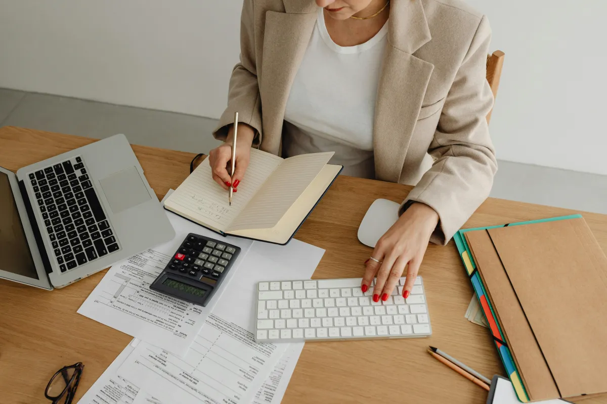 Hands using a calculator over payroll paperwork on a desk