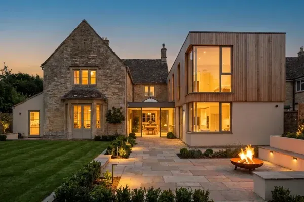 Architectural rendering of a home addition joined to a traditional house by a glazed connector at dusk