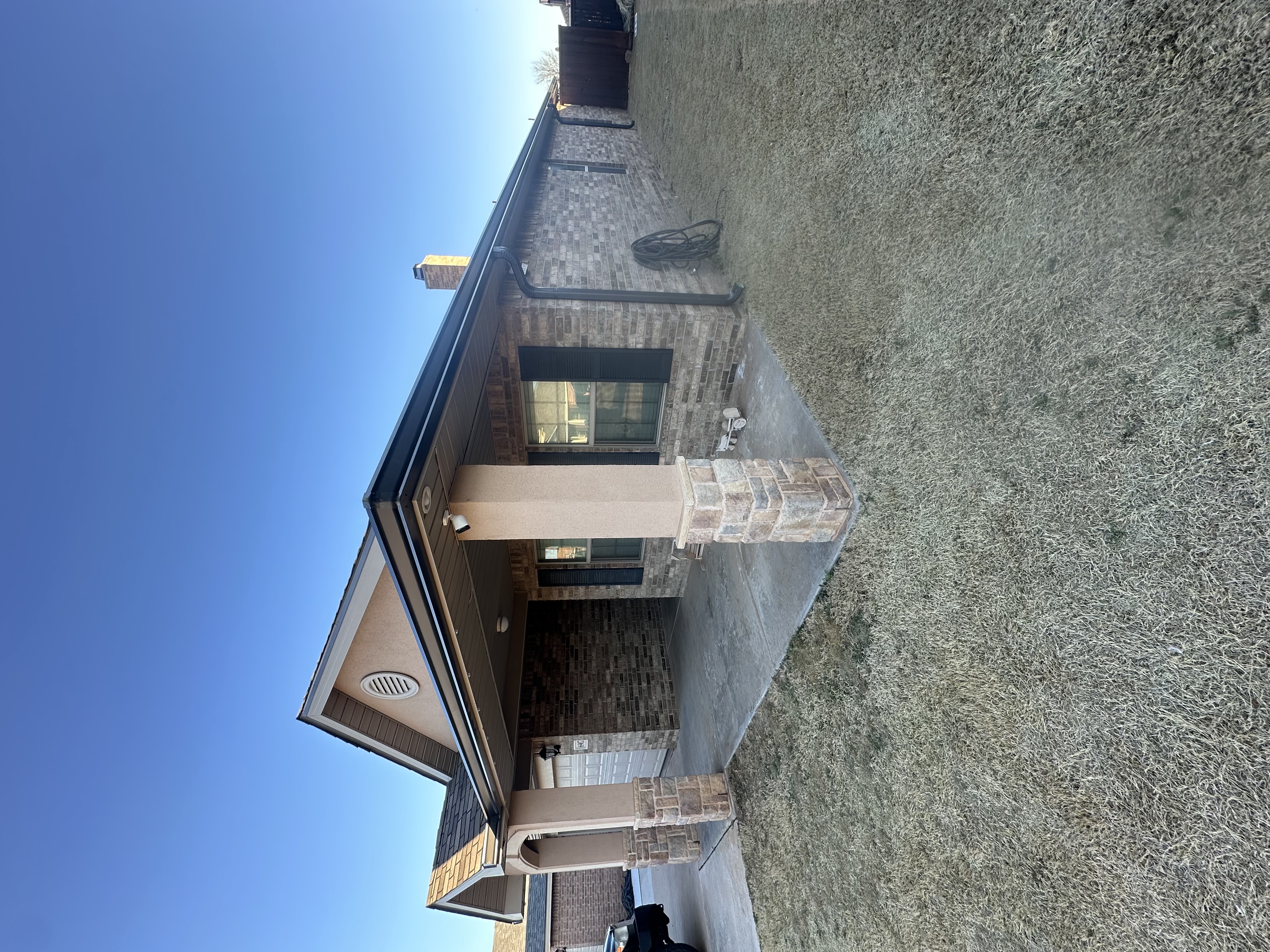 Technician installing seamless aluminum gutters at a residential home in Lubbock, Texas