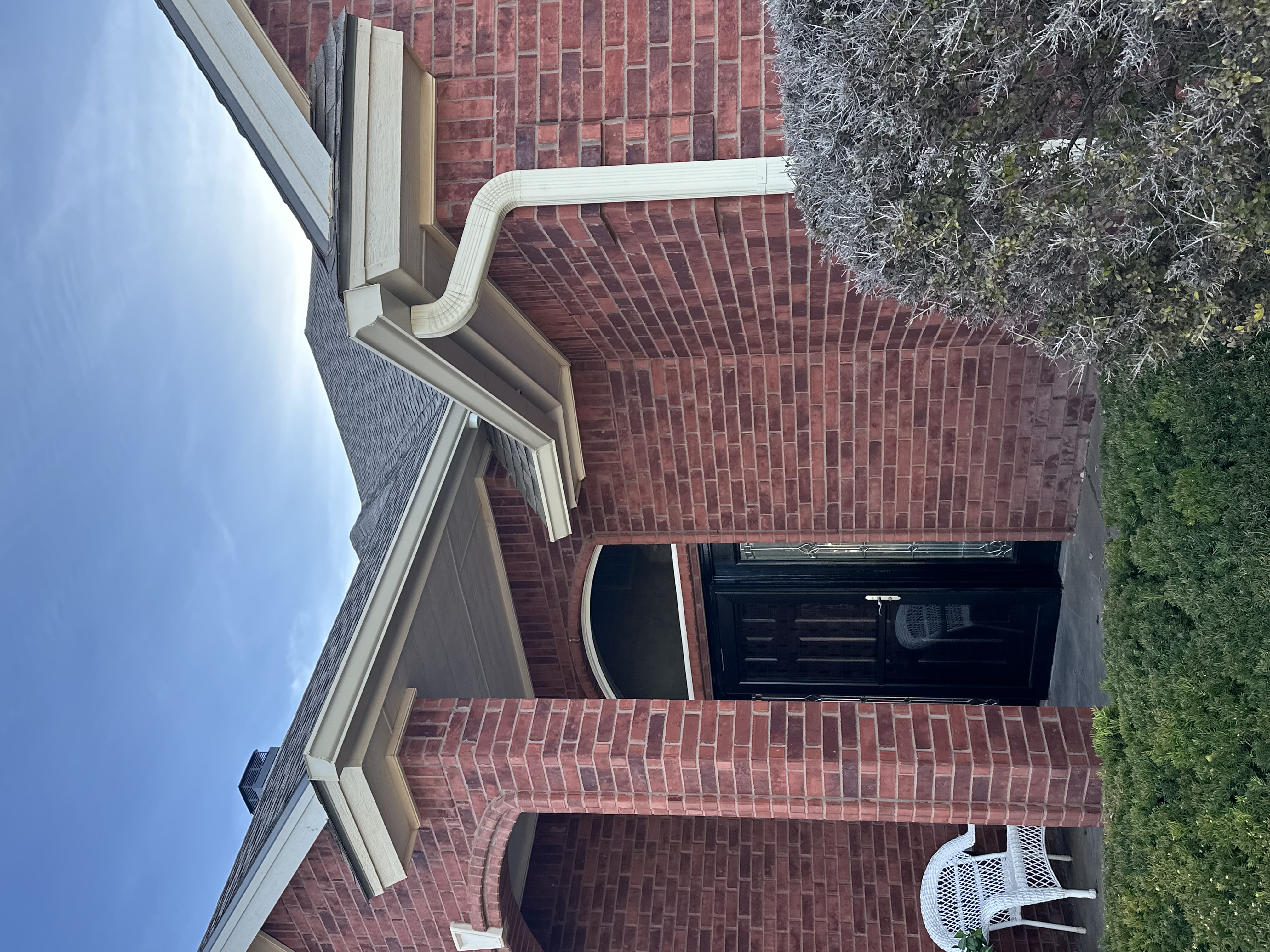 Technician installing seamless aluminum gutters at a residential home in Lubbock, Texas