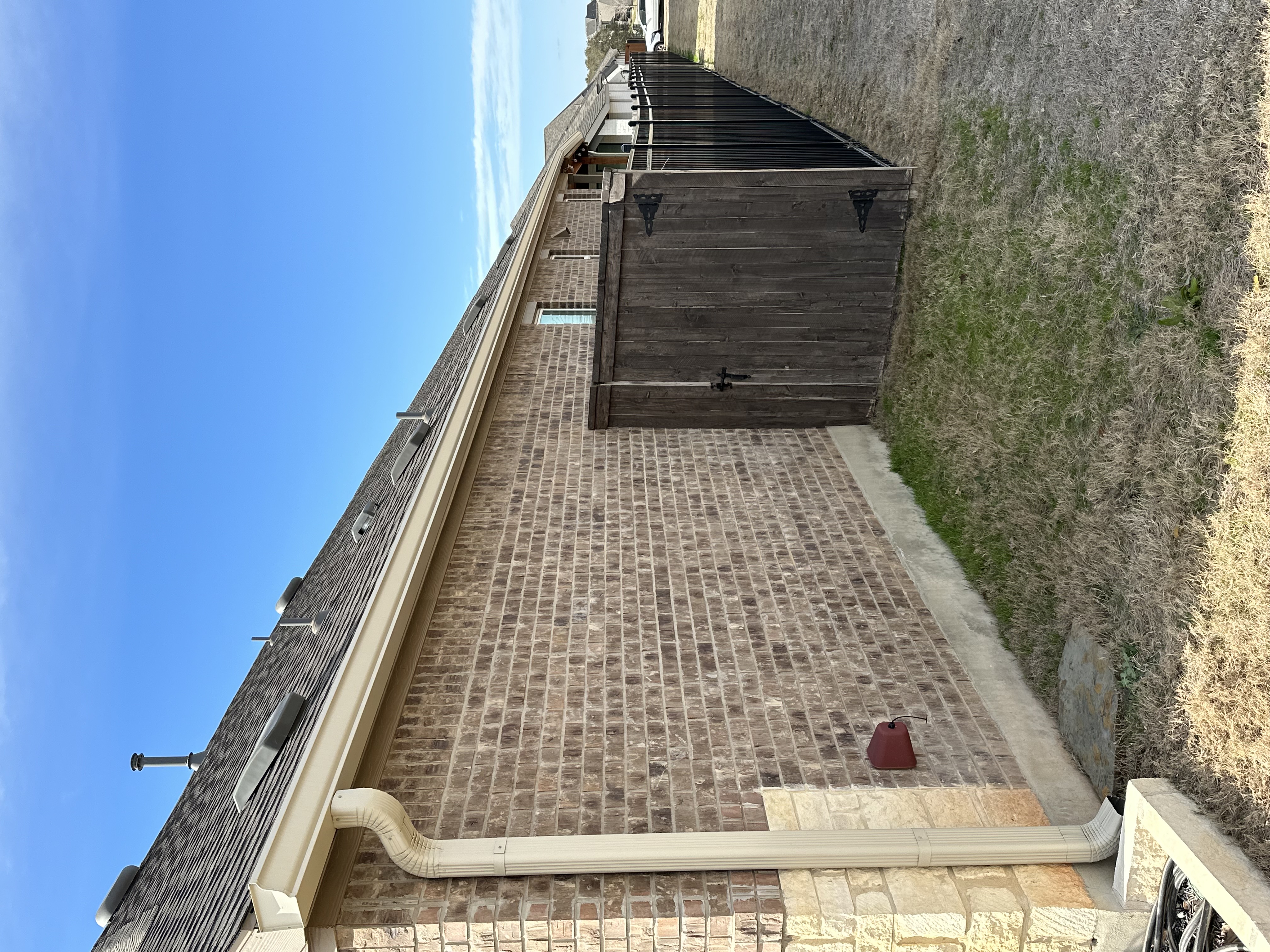 Technician installing seamless aluminum gutters at a residential home in Lubbock, Texas