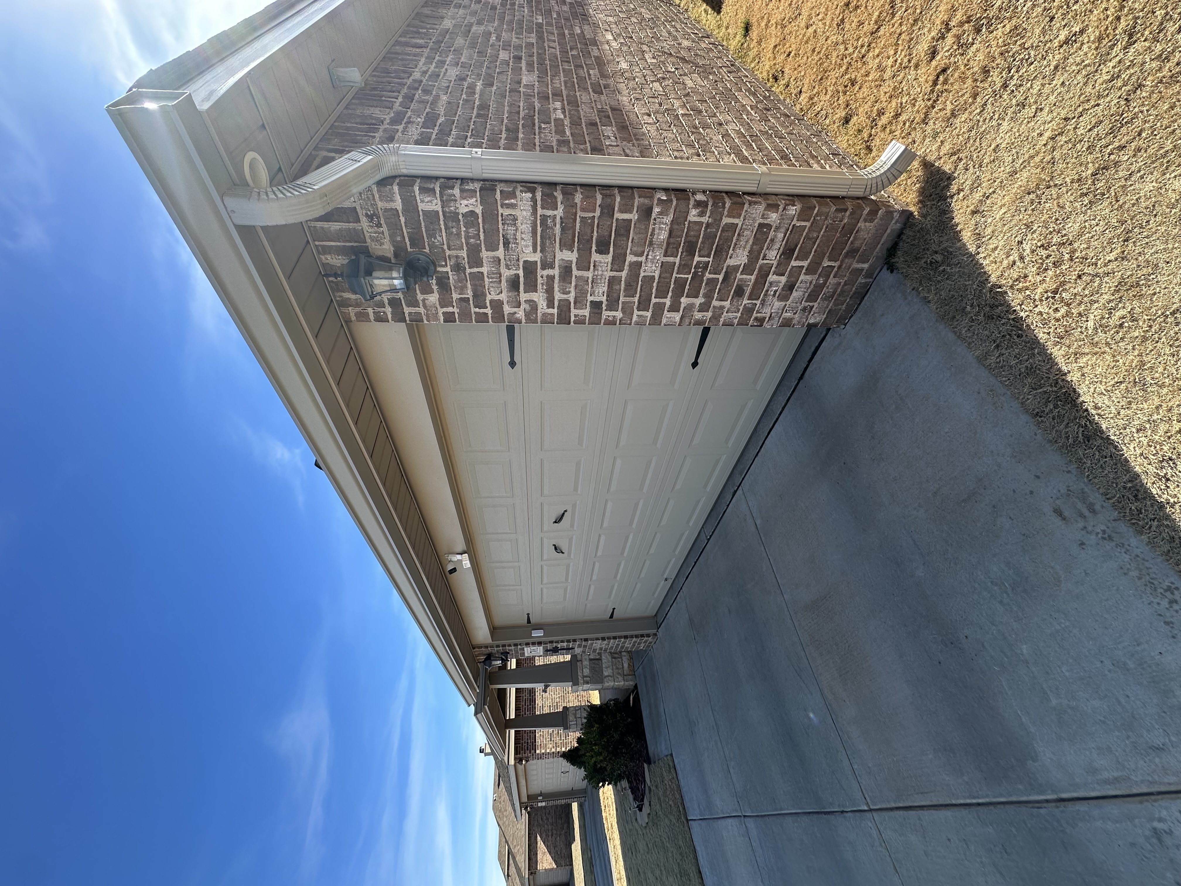 Technician installing seamless aluminum gutters at a residential home in Lubbock, Texas