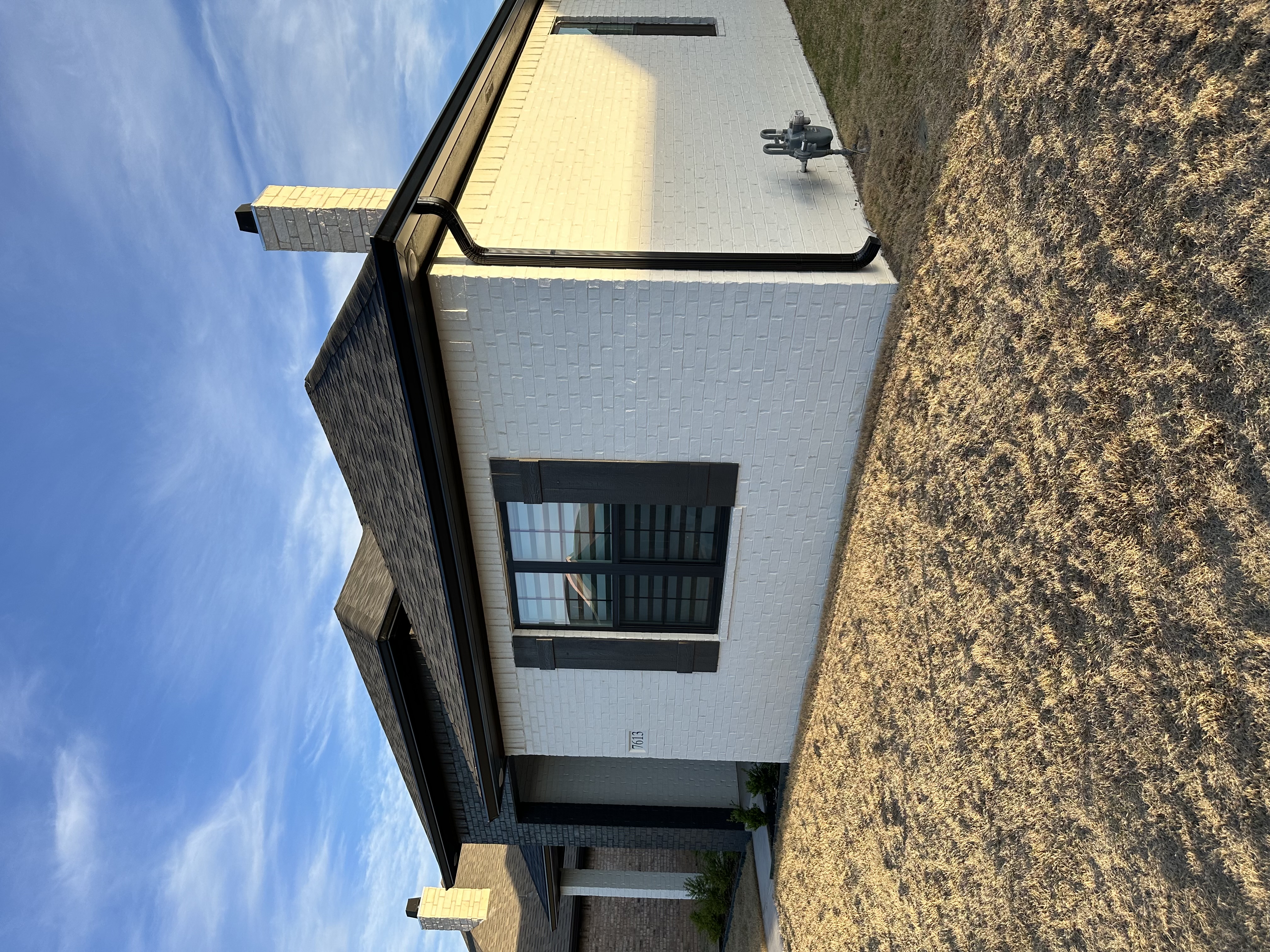 Technician installing seamless aluminum gutters at a residential home in Lubbock, Texas