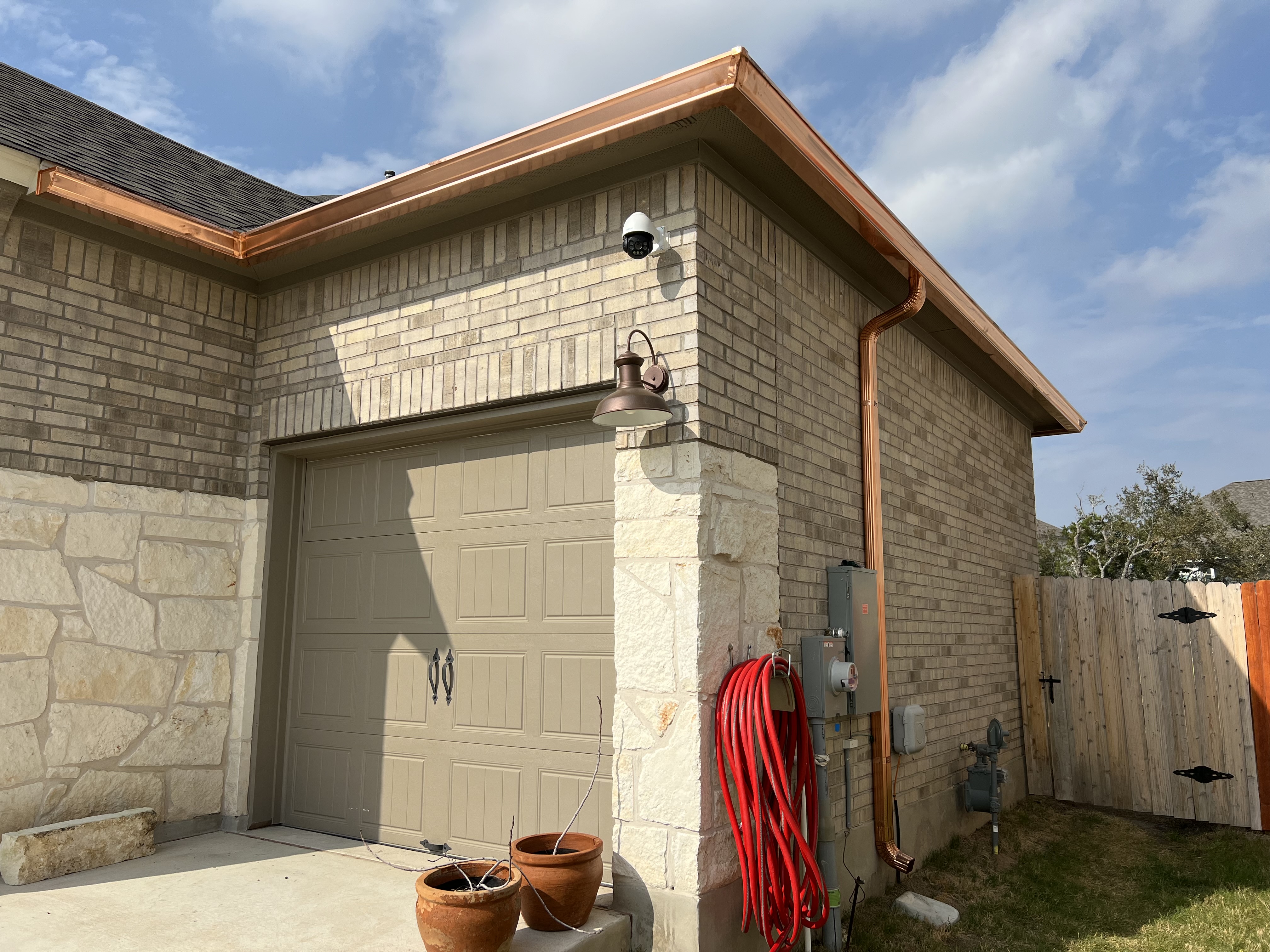 Technician installing seamless aluminum gutters at a residential home in Lubbock, Texas