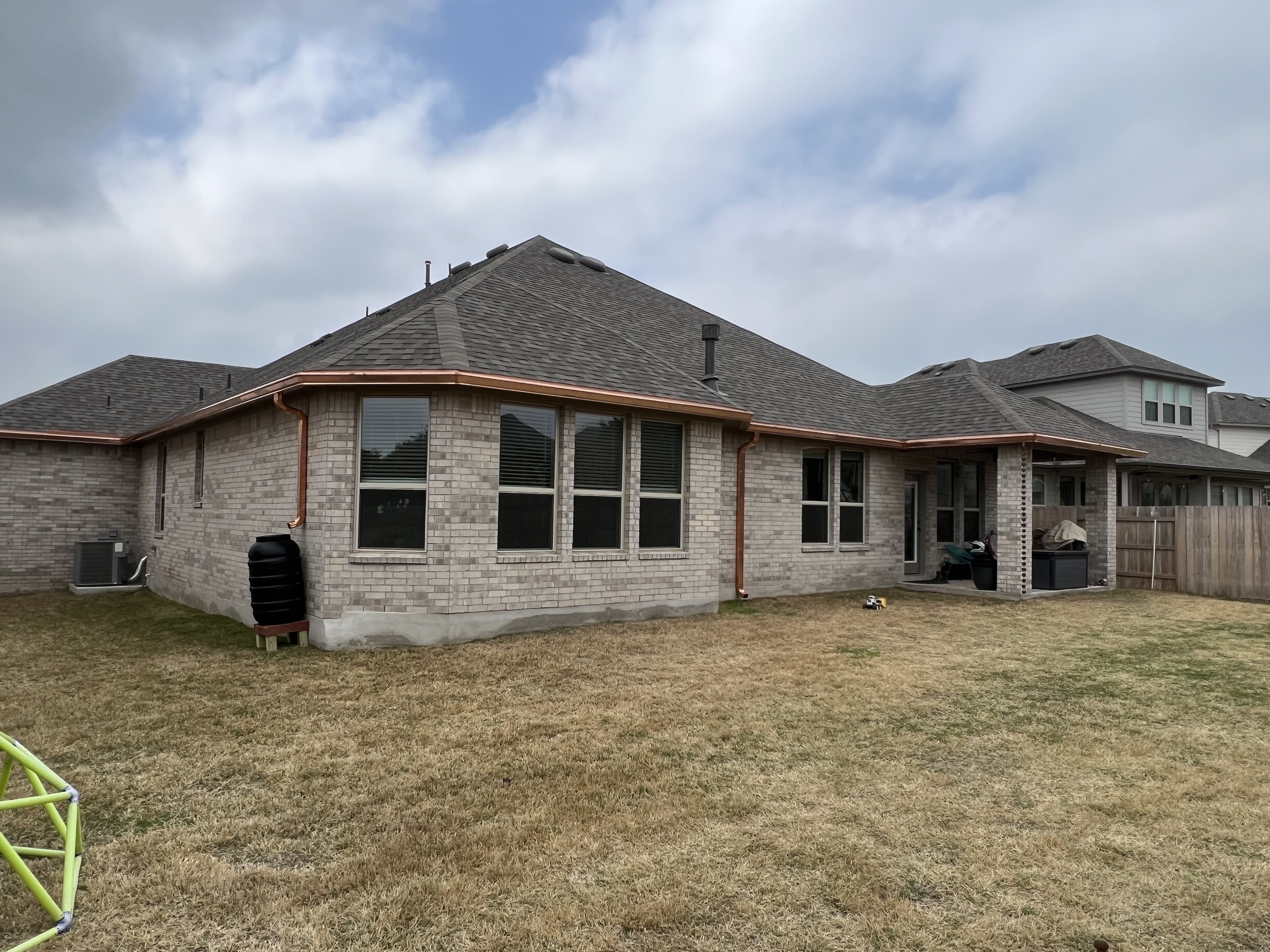 Technician installing seamless aluminum gutters at a residential home in Lubbock, Texas