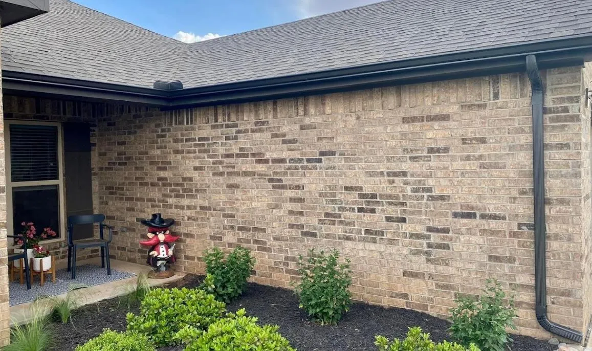 Technician installing seamless aluminum gutters at a residential home in Lubbock, Texas