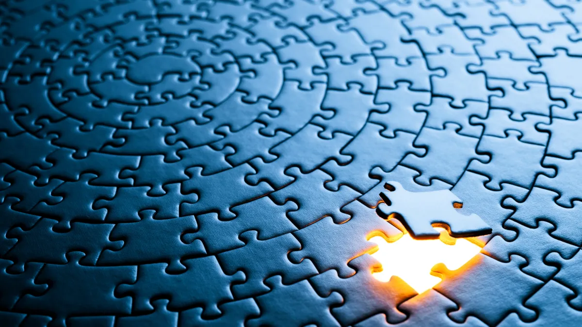 a circular jig saw puzzle in deep blue with one piece missing which is backlit - signifying and highlighting the missing piece