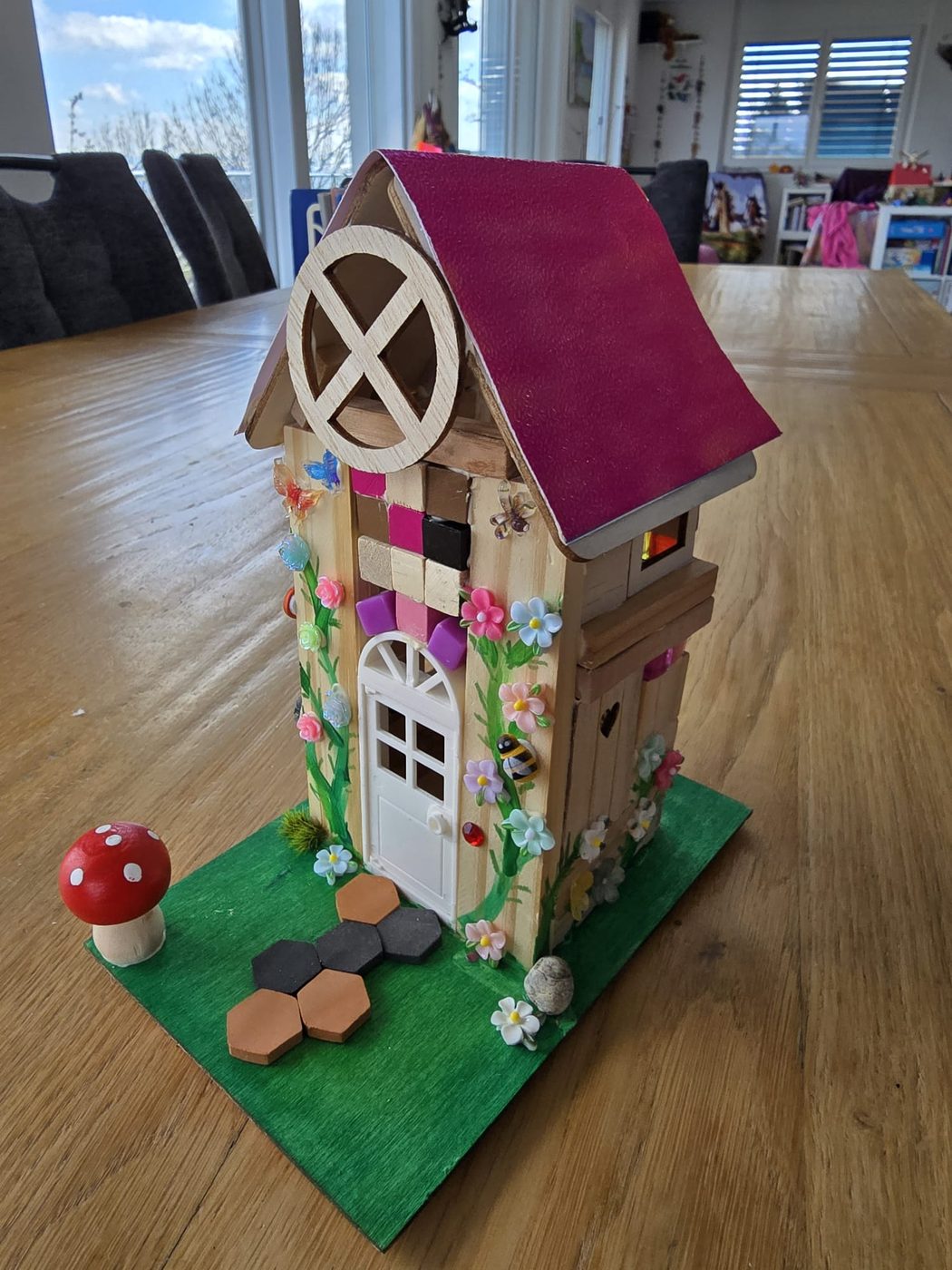 Ein selbst gebautes Traumhaus aus Holz mit Blumen und Fliegenpilz