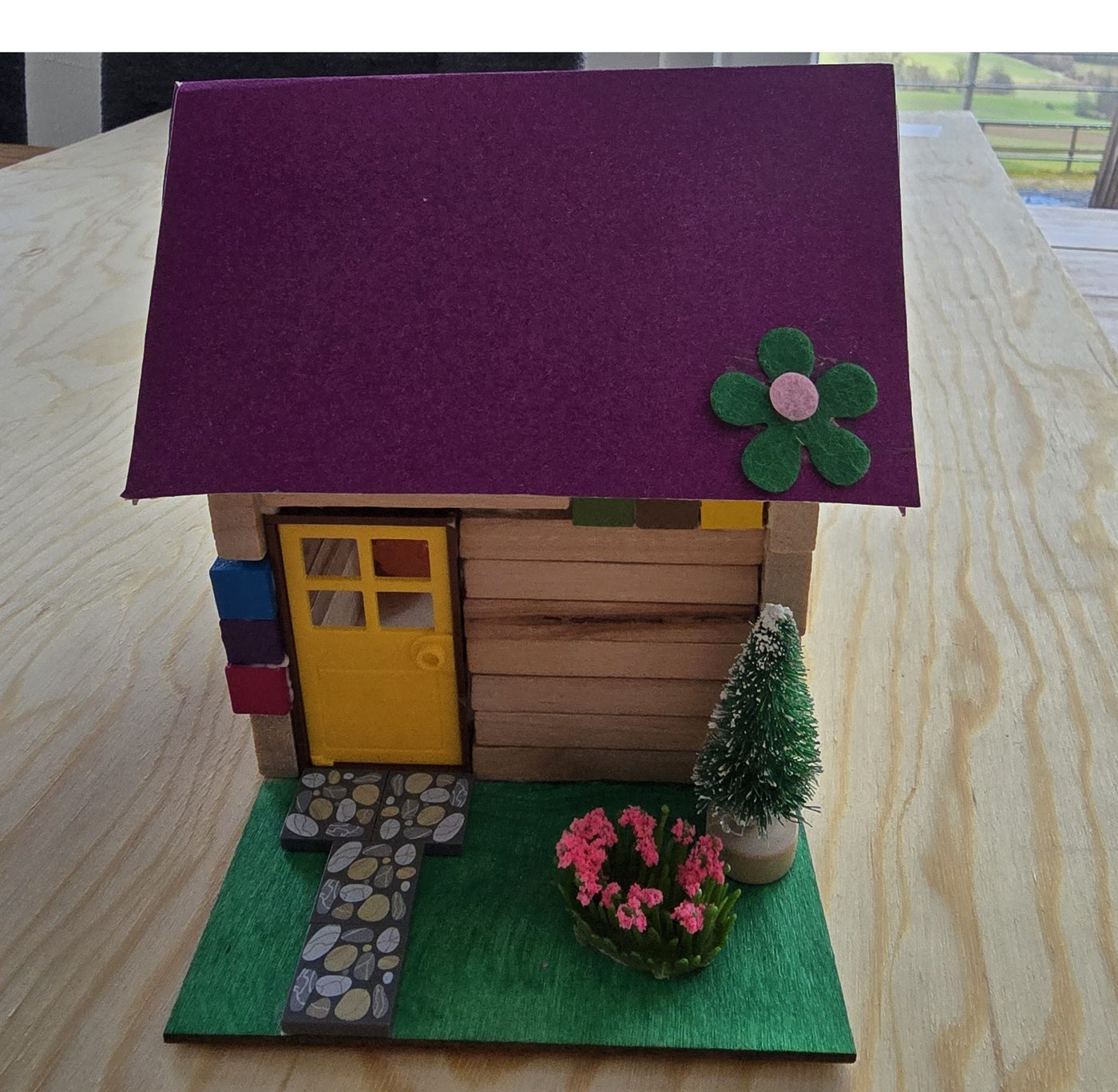 Ein selbst gebautes Mini-Haus aus Holz mit lila Dach und gelber Tür