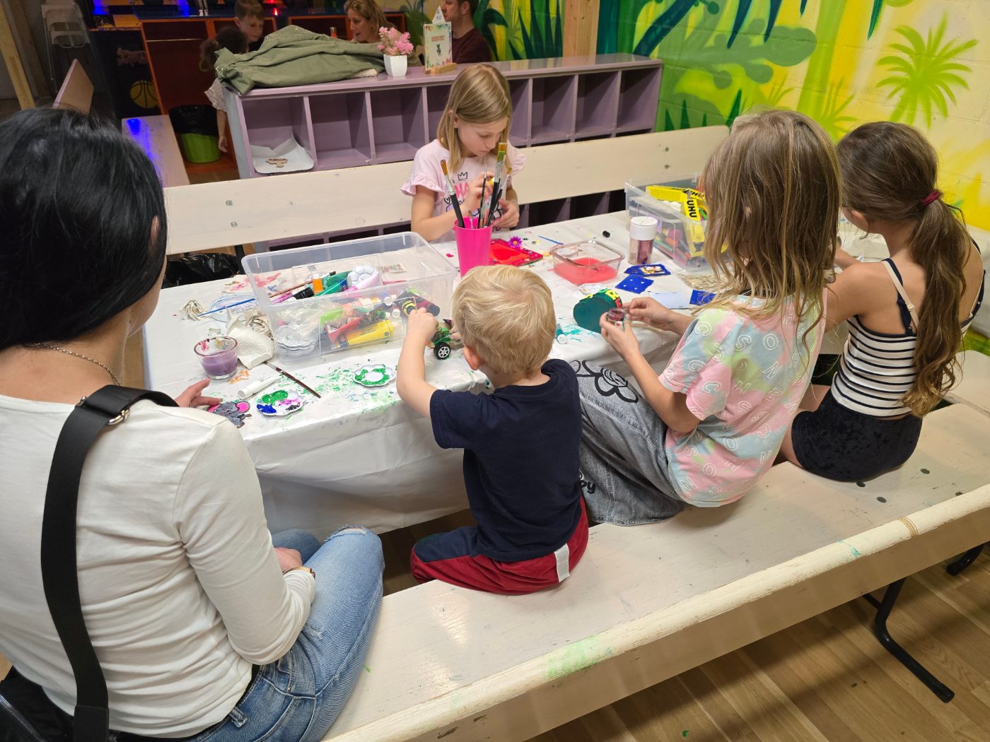 Kinder gestalten an einem langen Basteltisch