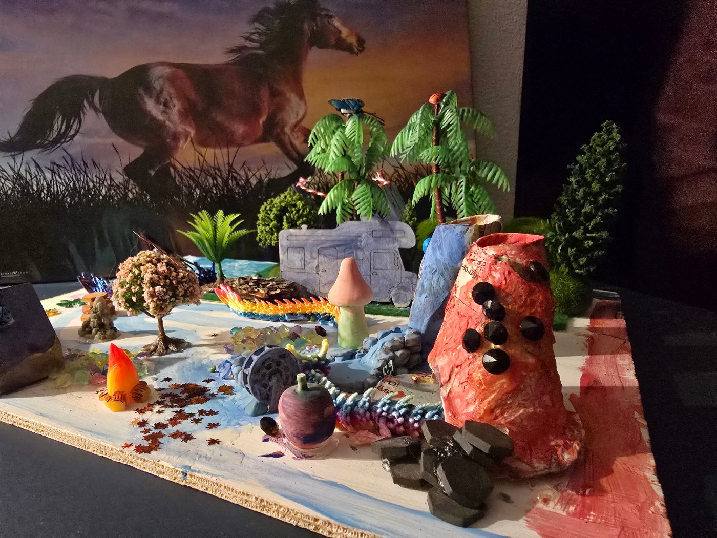 Ein Mini-Wonderland mit Palmen, Vulkan und Fluss auf einer Holzplatte