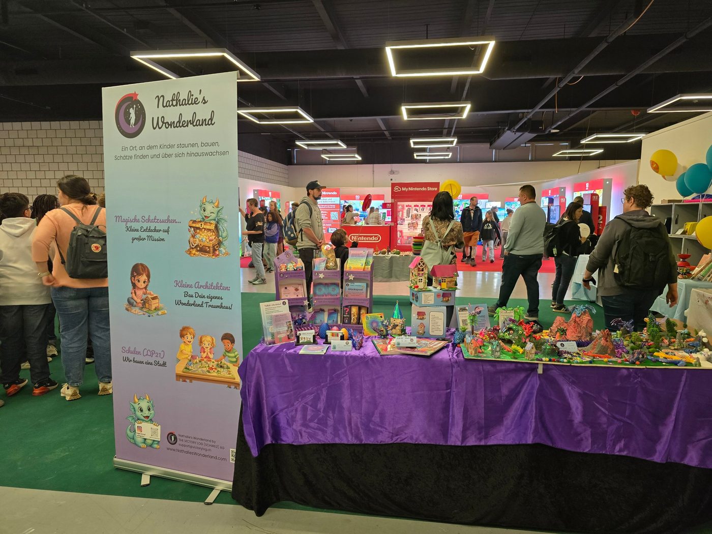 Der Stand von Nathalie's Wonderland an der BEA in Bern, mit lila Tisch, Häusern und Drachenwelten
