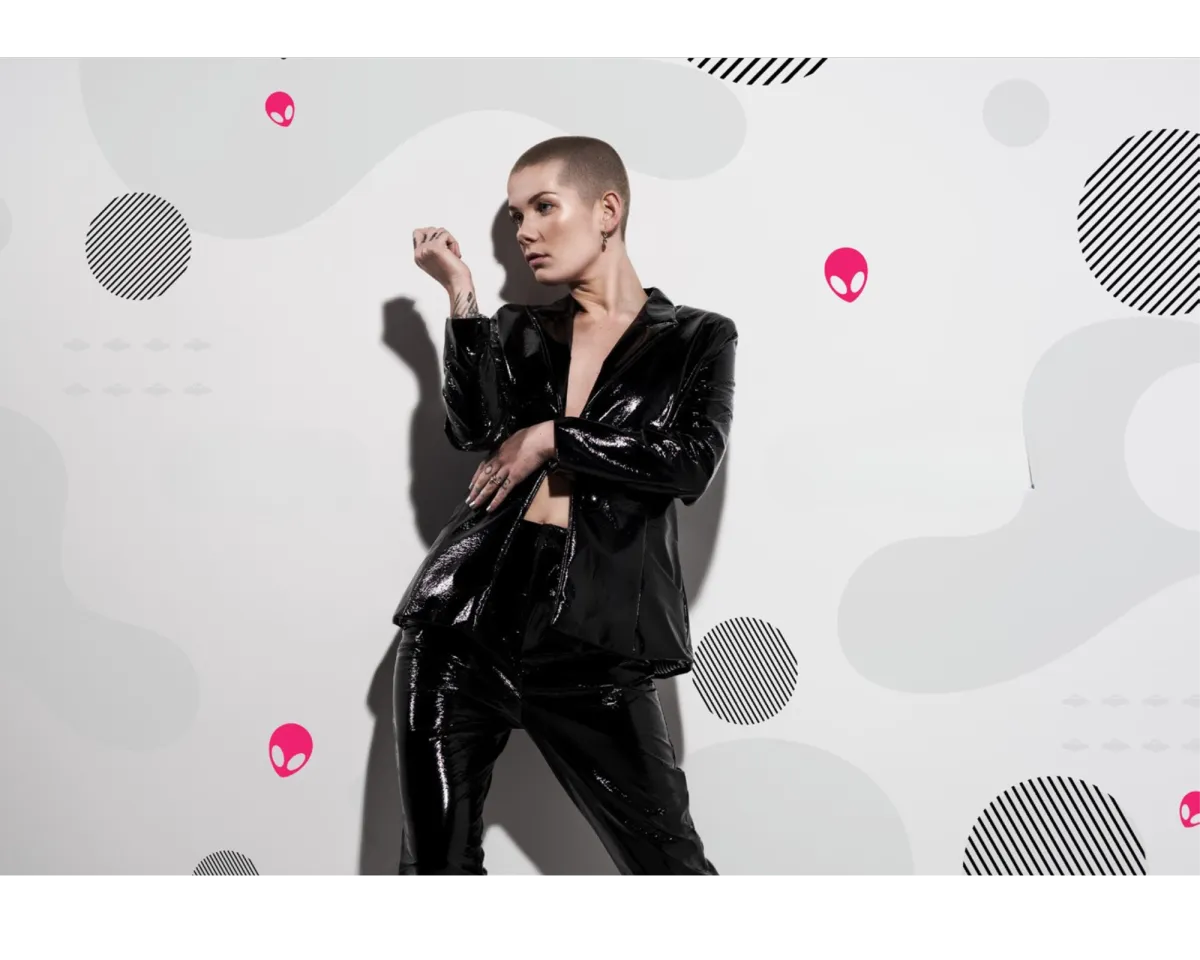 Alyx Steele stands confidently at a bustling New York City crosswalk, holding a passport and a guidebook, with iconic skyscrapers in the background. The image is vibrant, modern, and welcoming, capturing the excitement of starting a new life in the USA. 3:2 aspect ratio.