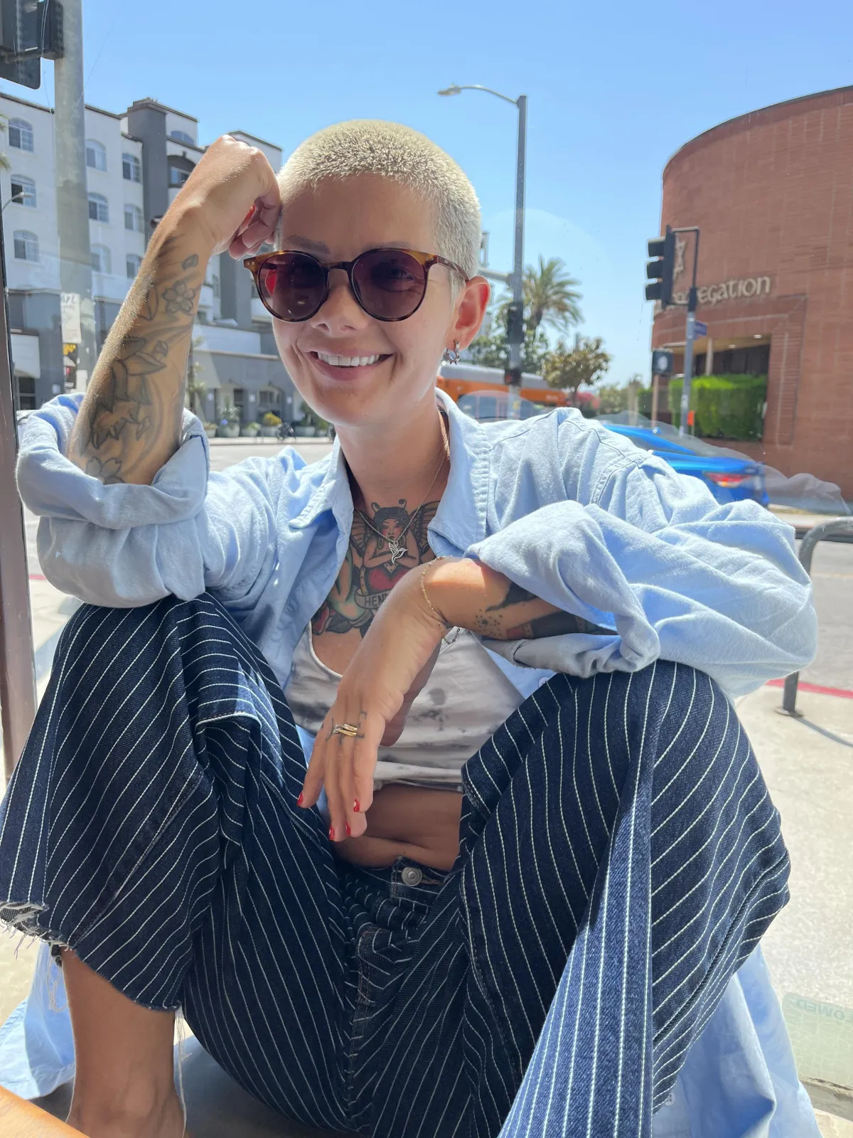 Alyx Steele, a British woman in her early 30s, smiles warmly in a sunlit home office decorated with both UK and US memorabilia. She sits at a desk with a laptop and coffee, exuding approachability and expertise. 1:1 aspect ratio.