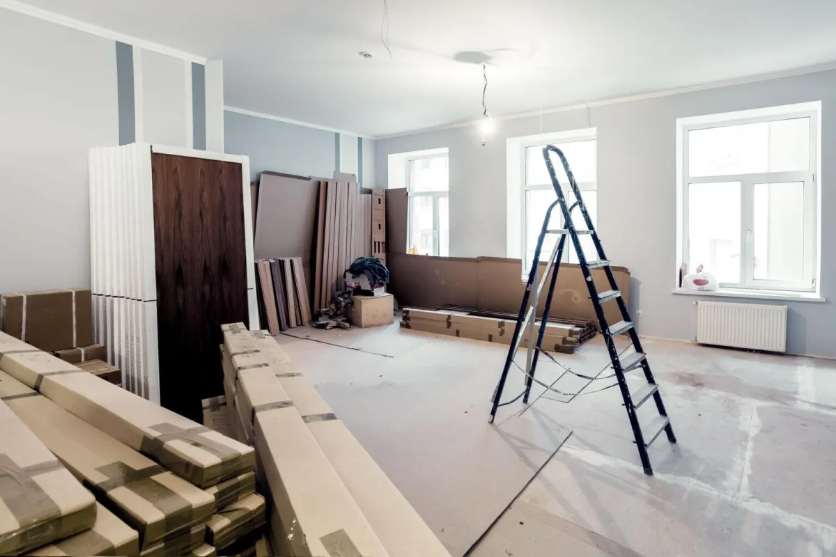 Renovation space with stacked flooring materials, a ladder, and unfinished walls, illustrating AFB Floors' expertise in flooring installation and community upgrades.