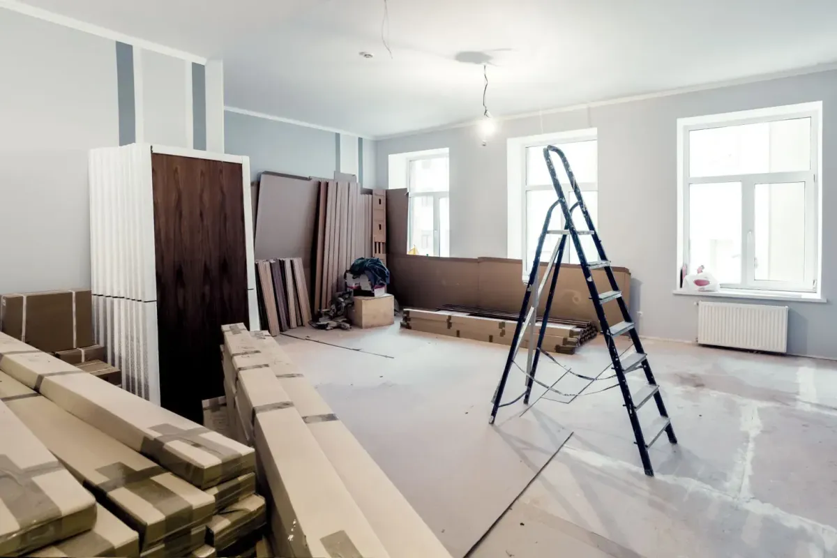 Renovation space with stacked flooring materials, a ladder, and unfinished walls, illustrating AFB Floors' expertise in flooring installation and community upgrades.