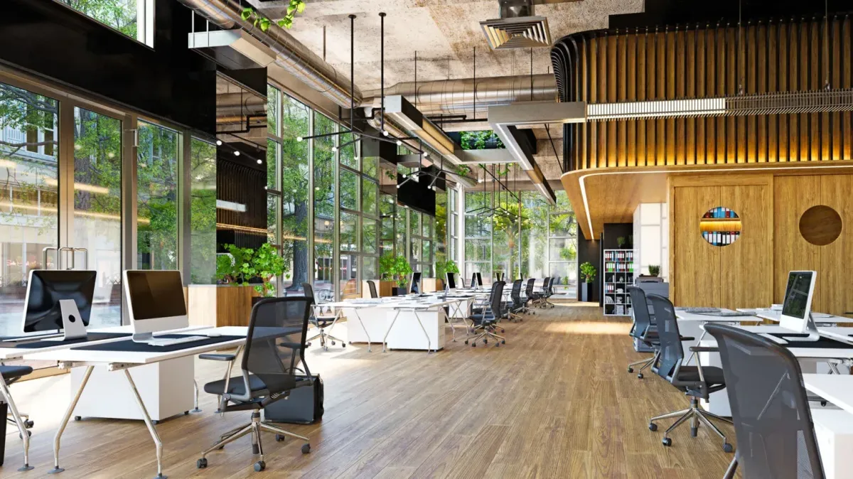 Modern office interior with large windows, wooden flooring, and stylish desks, showcasing a collaborative workspace ideal for renovation and construction projects in rental properties.