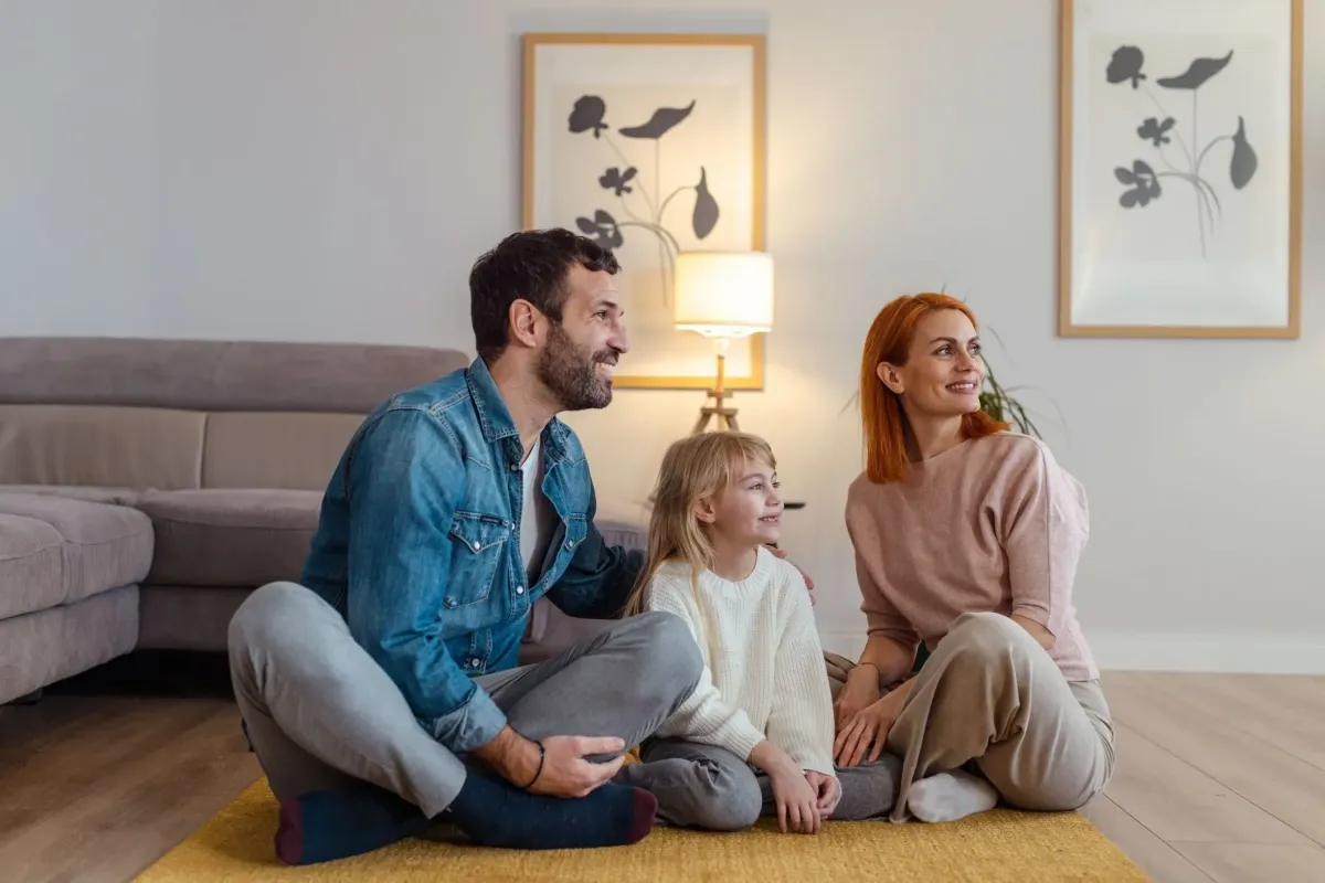 Happy family sitting on living room floor, smiling together – representing comfort and quality flooring from AFB Floors.