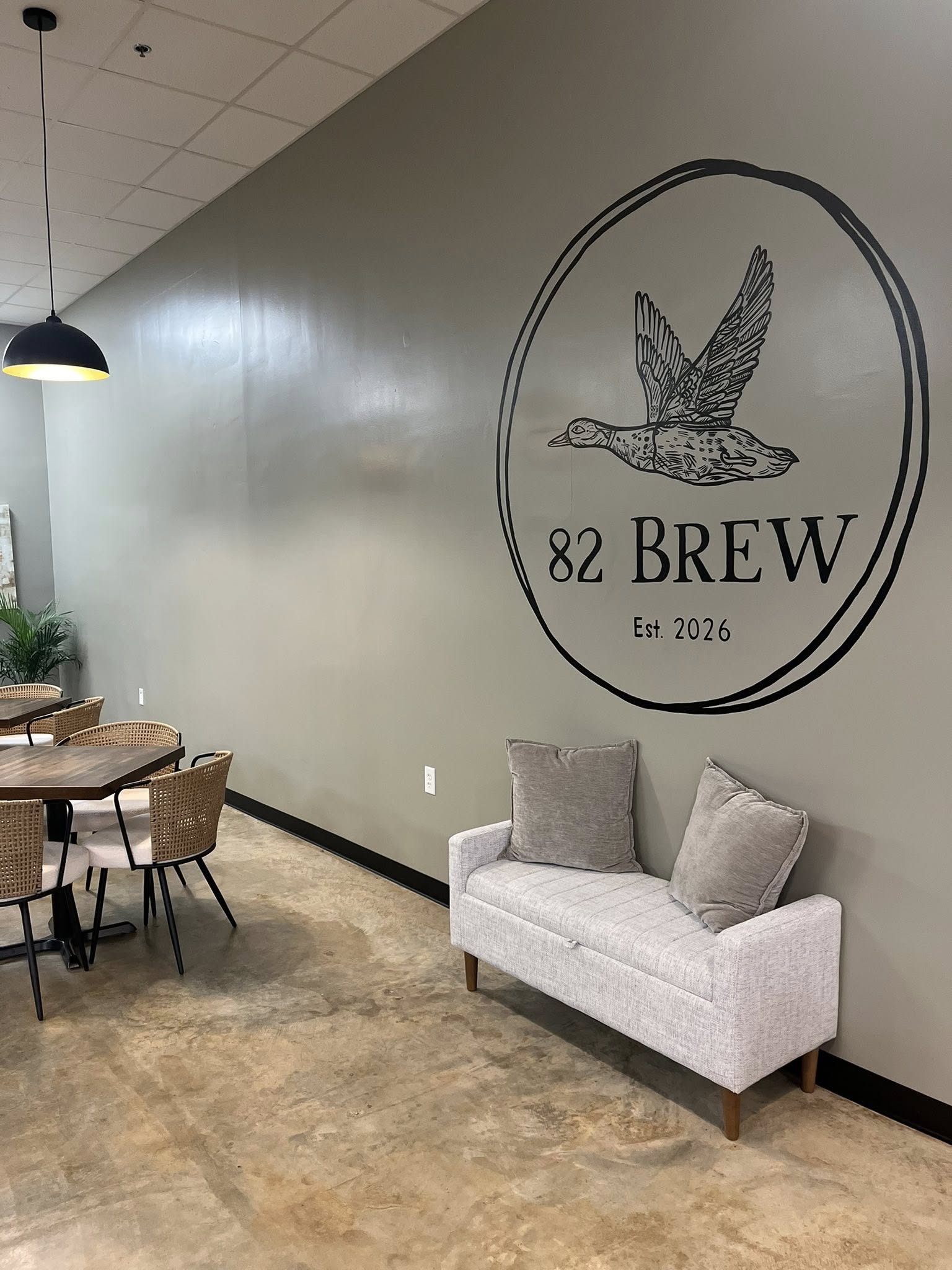 82 Brew coffee shop interior seating area with logo wall in Dawson Georgia