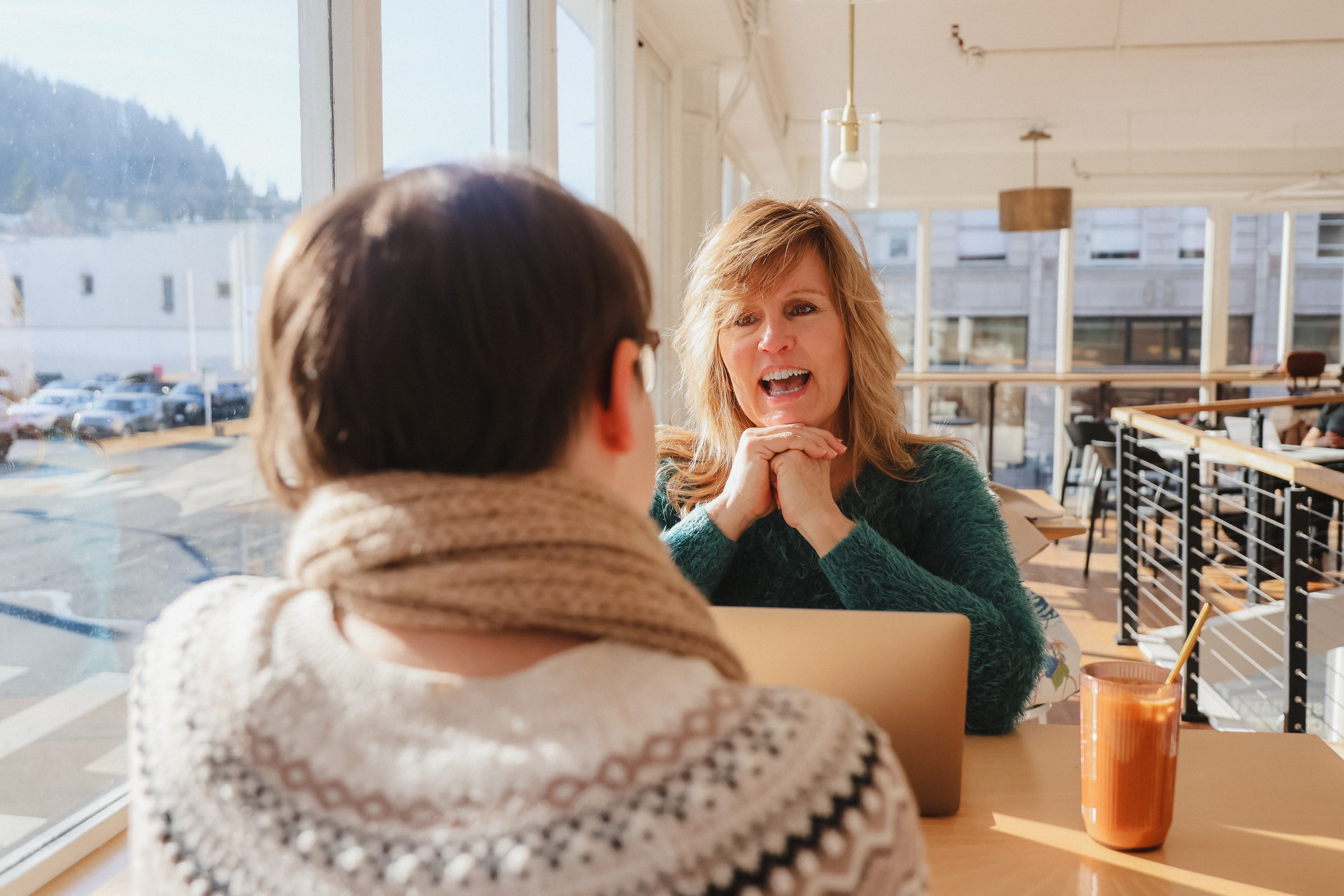 A woman with glasses intently listening during a business meeting, surrounded by colleagues.