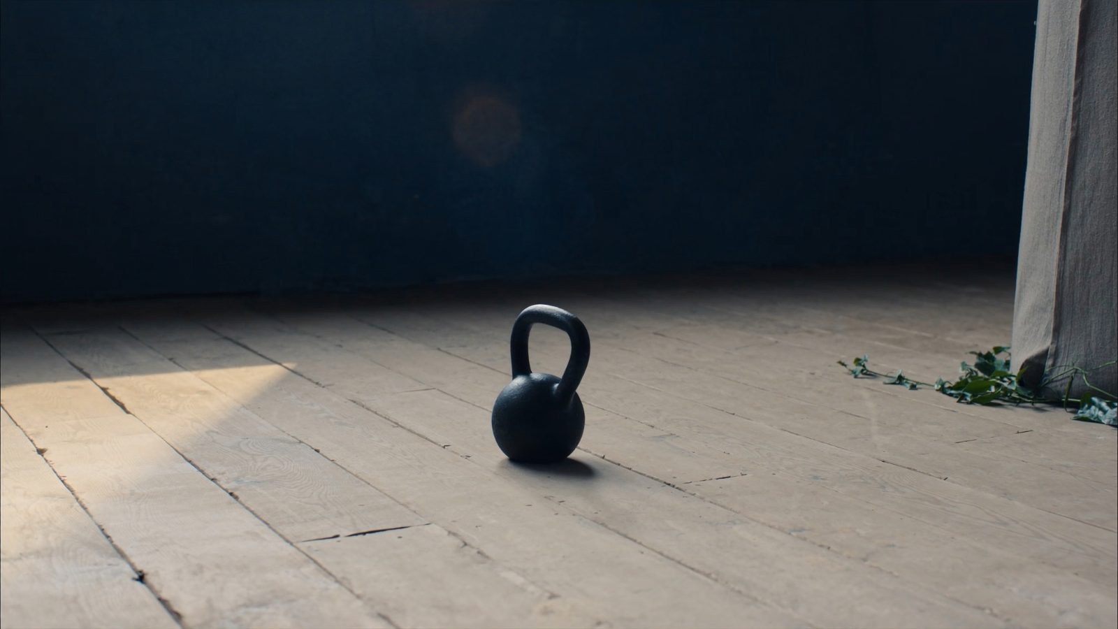 A single cast-iron kettlebell resting on a sunlit wooden floor in a quiet, spare room, representing communication skill built one rep at a time