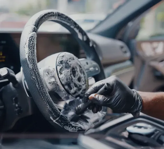 Mercedes Benz steering wheel being brush cleaned with soap and fine detailing hand bush.