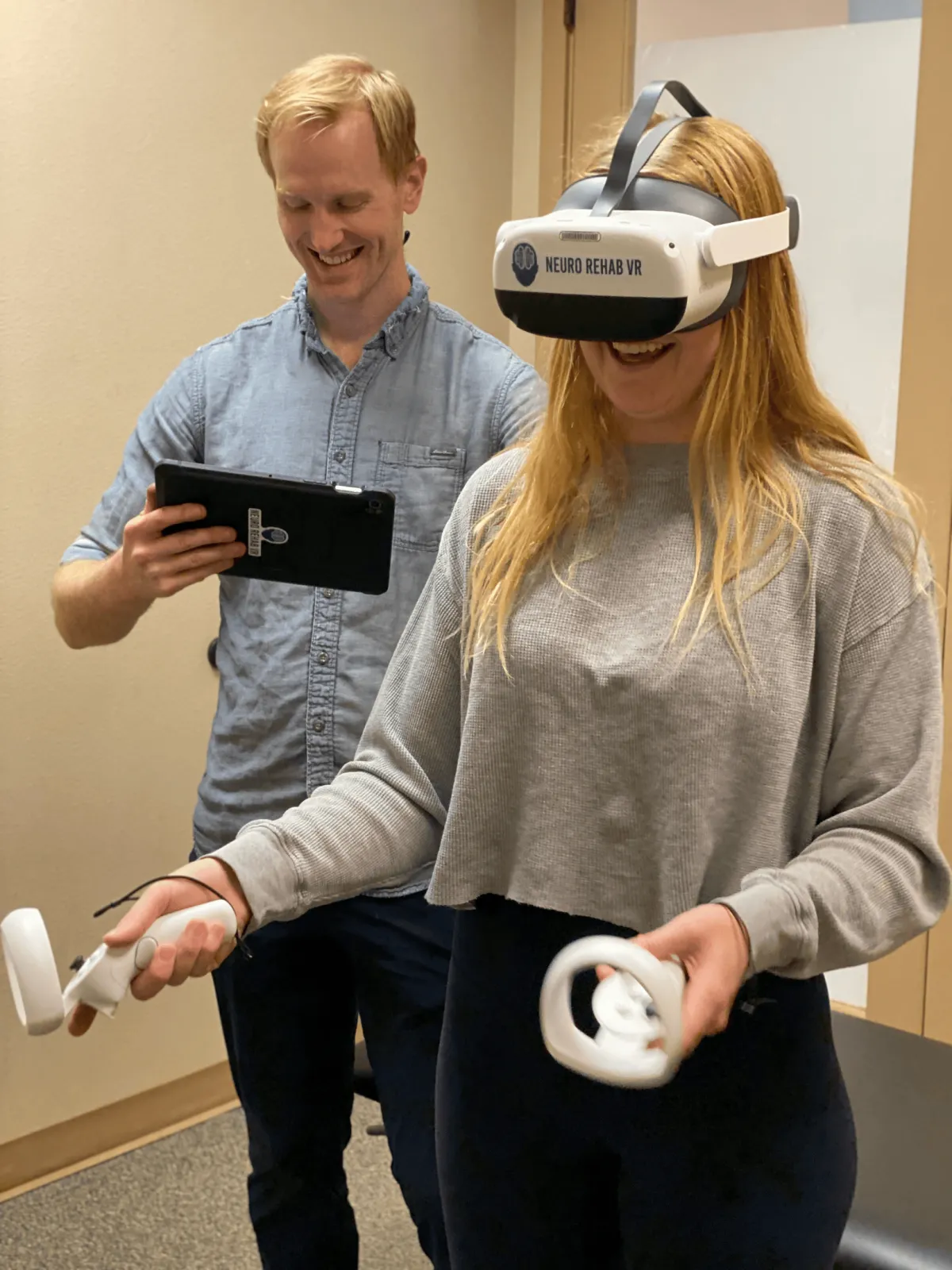 A smiling patient engages with a Virtual Reality physical therapy session under the supervision of a PhysioFIT therapist, showcasing the interactive and innovative treatment approach.