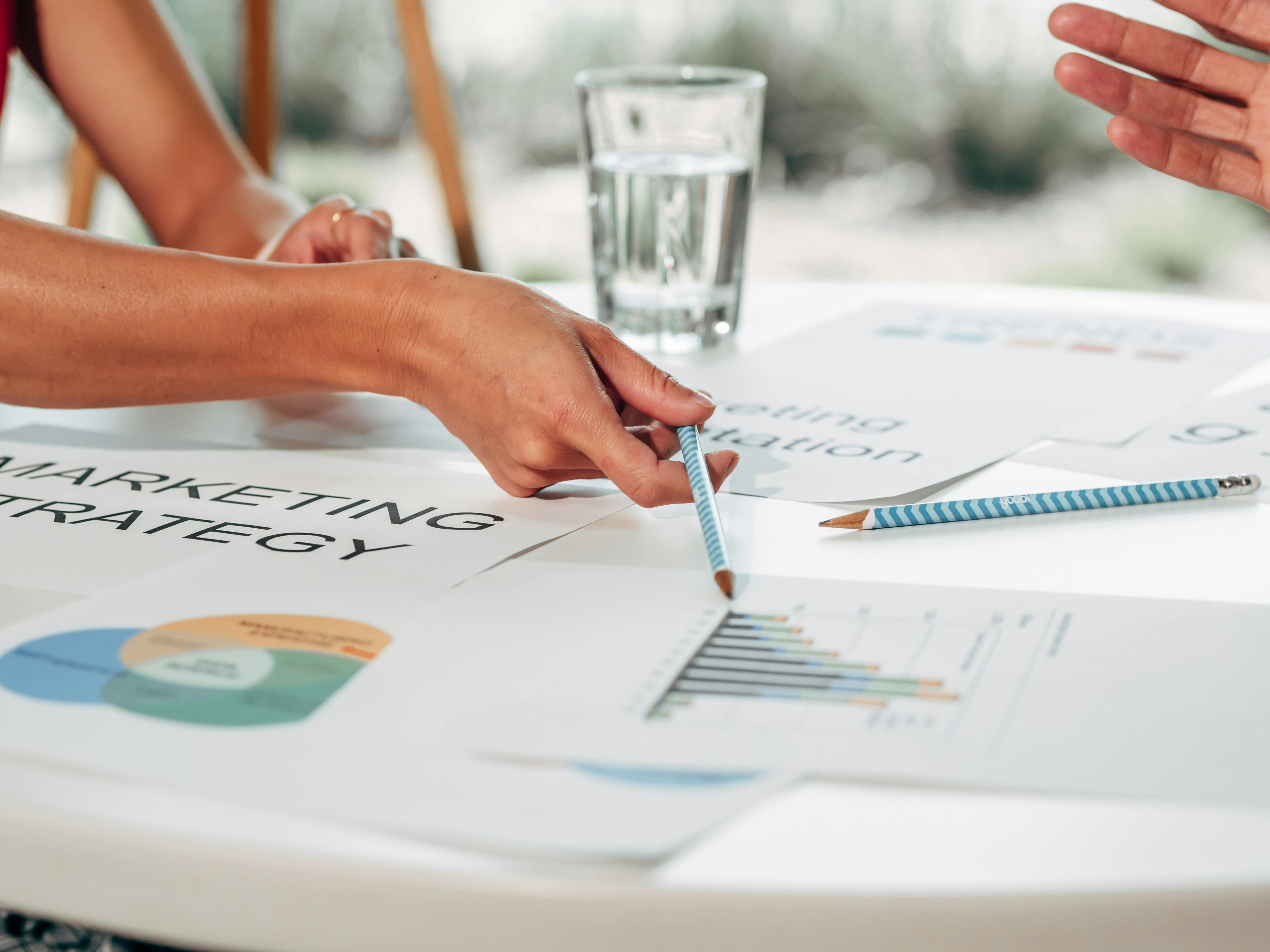 Image of someone pointing to a sheet of paper with marketing strategy written on it