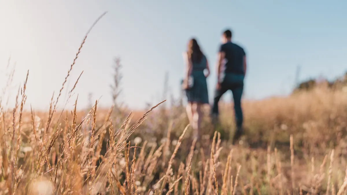 a young couple in a open field walking away