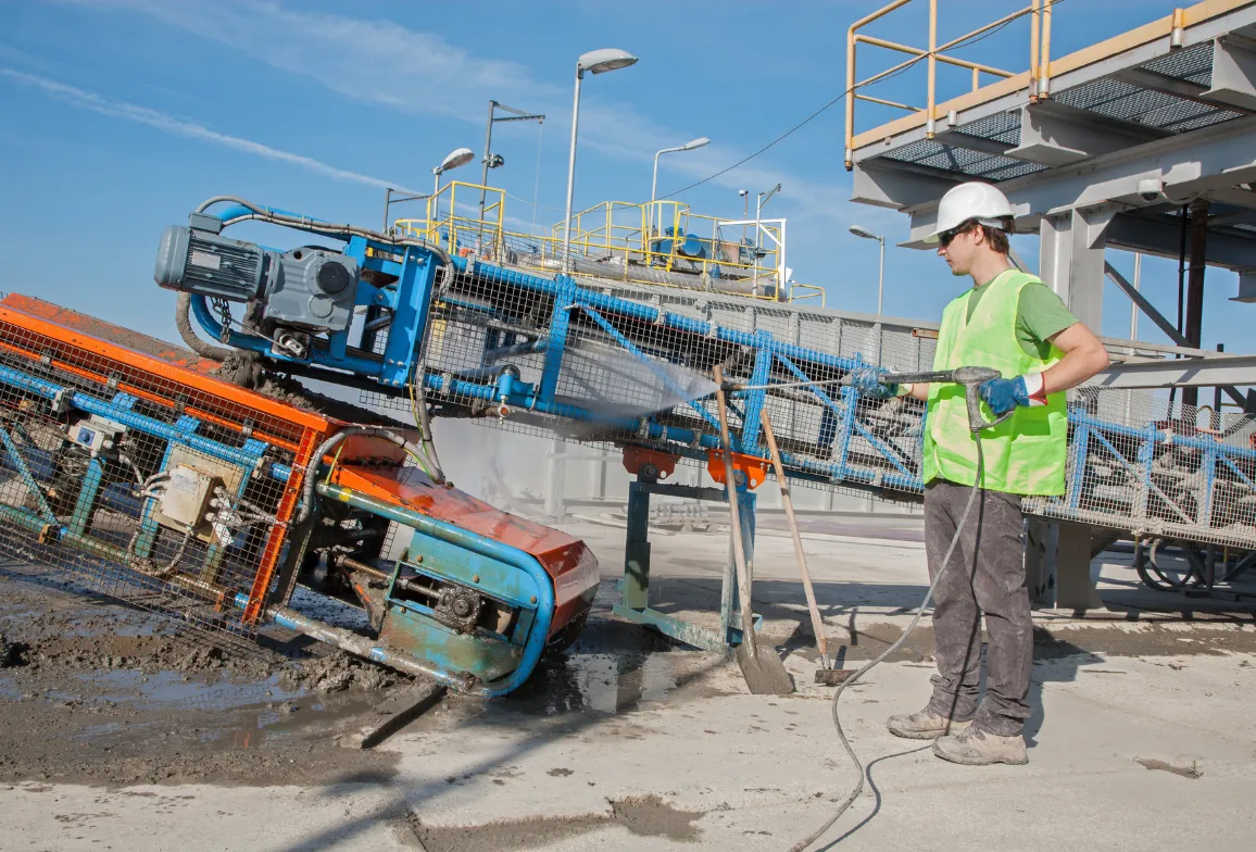 Man cleaning industrial equipment with pressure washer