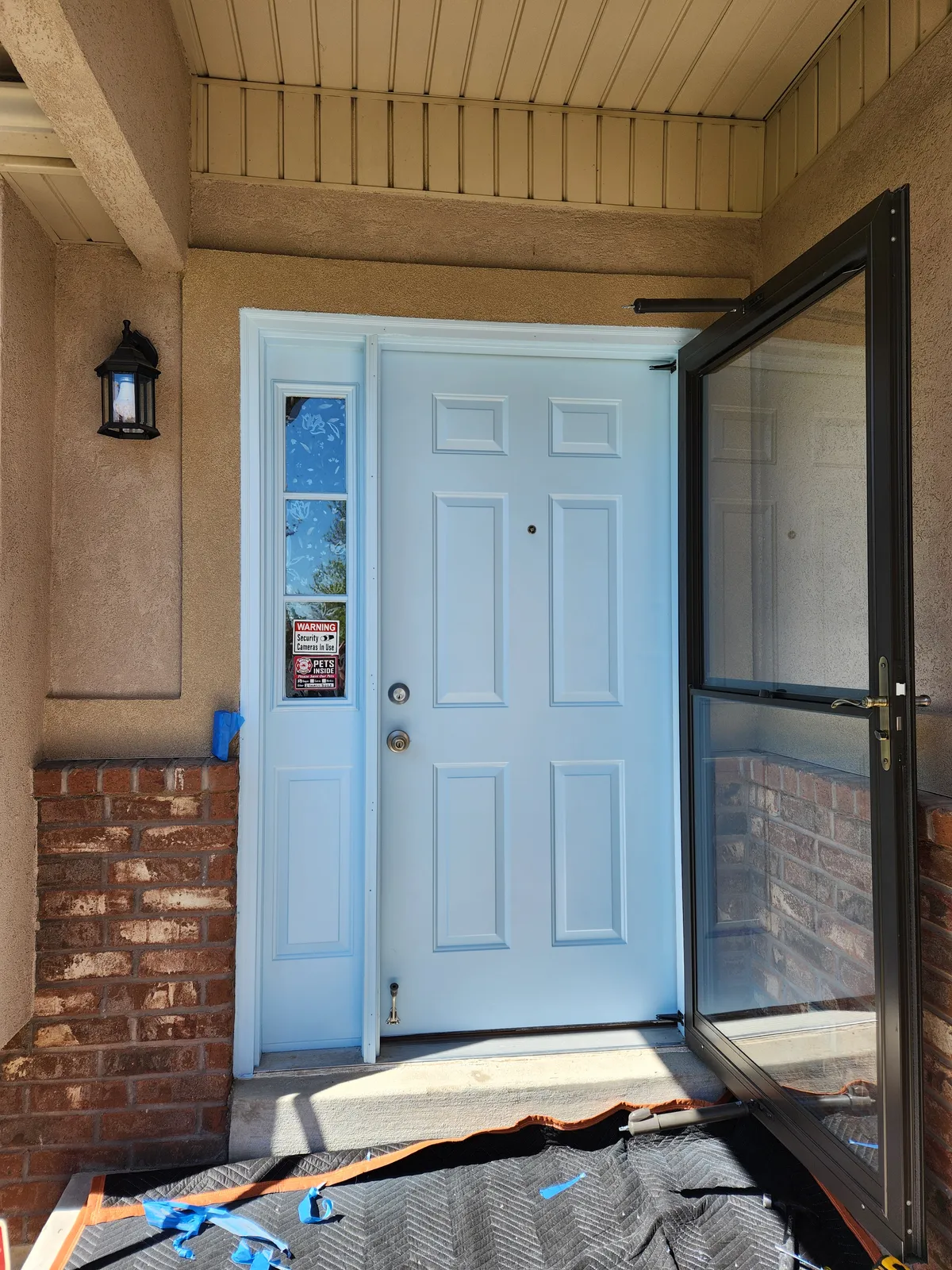White entry door with sidelights and a black storm door
