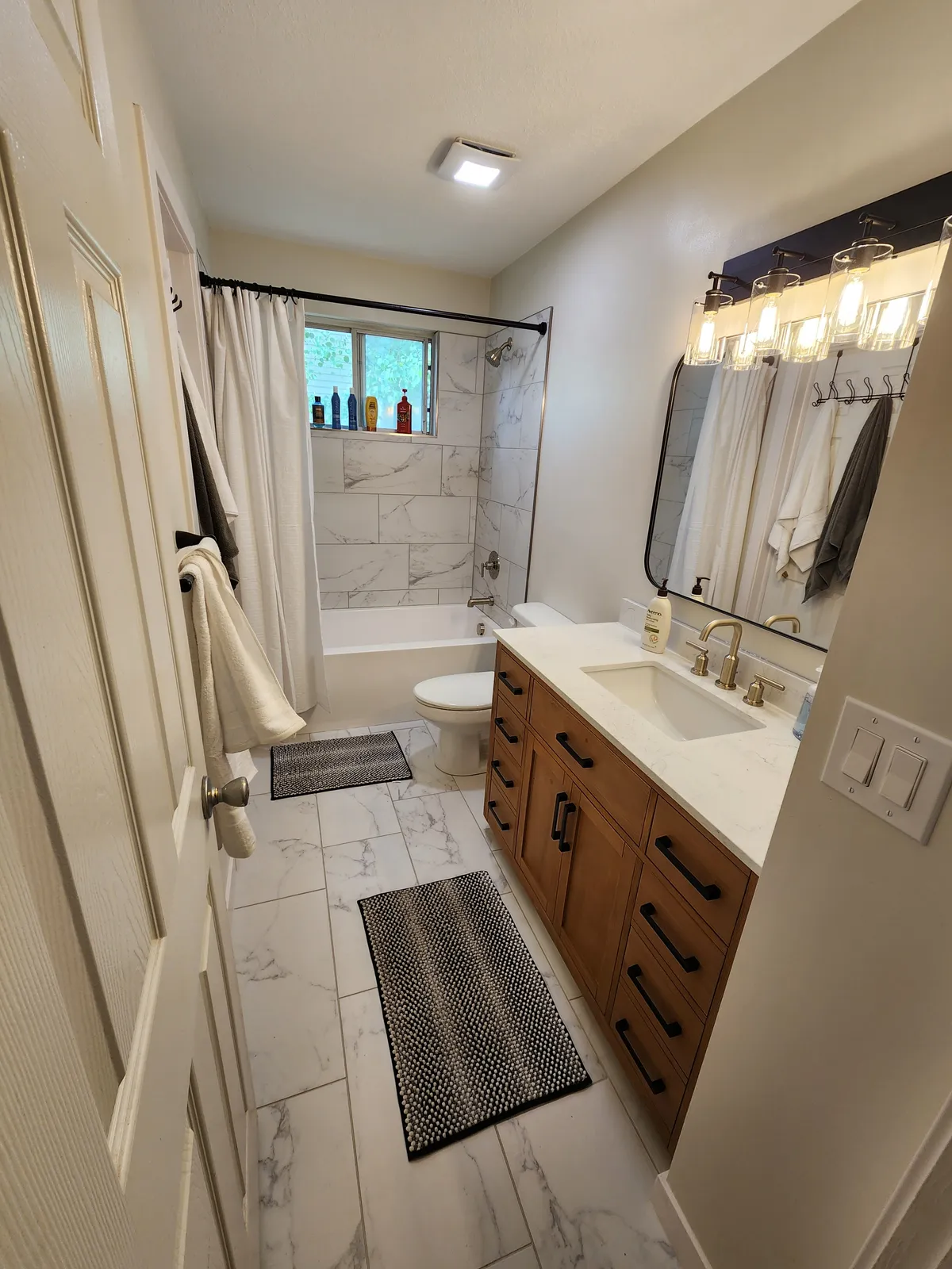 Bathroom remodel by Handyman’s Corner with tile, a shower curtain, and a wood vanity