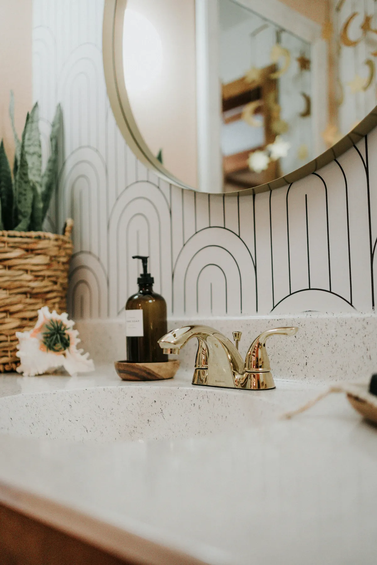 Brass bathroom faucet with a white countertop and tiled backsplash