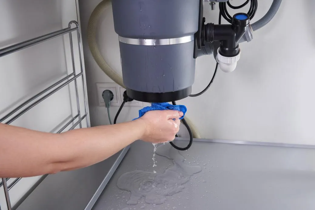 Garbage disposal repair technician working under kitchen sink”